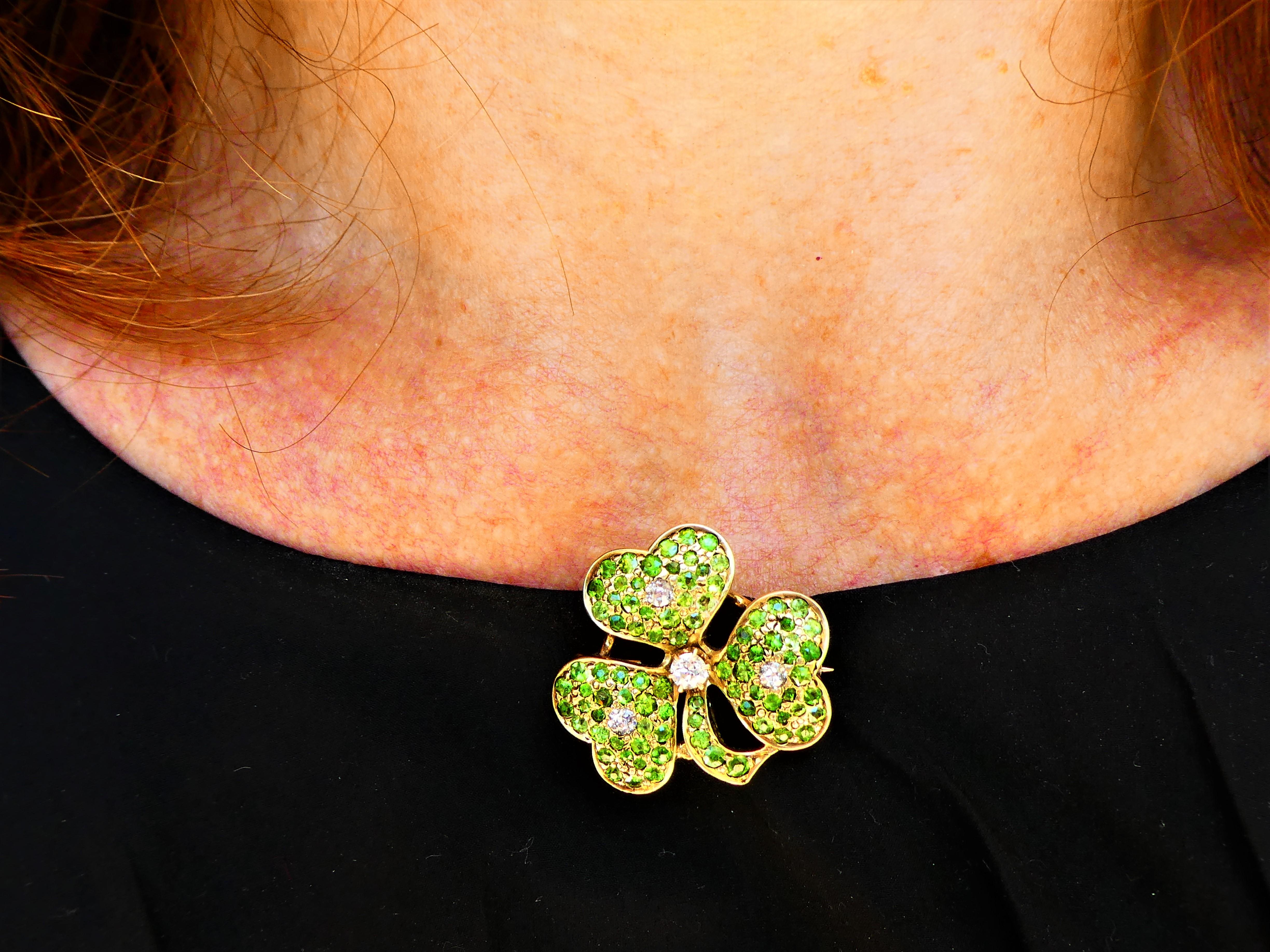 This lovely brooch was crafted around 1900 in 14 karat yellow gold in the shape of a shamrock with three leaves. The rare green demantoid garnets are pavé set and each leave has one round diamond in the center. The largest diamond is located between