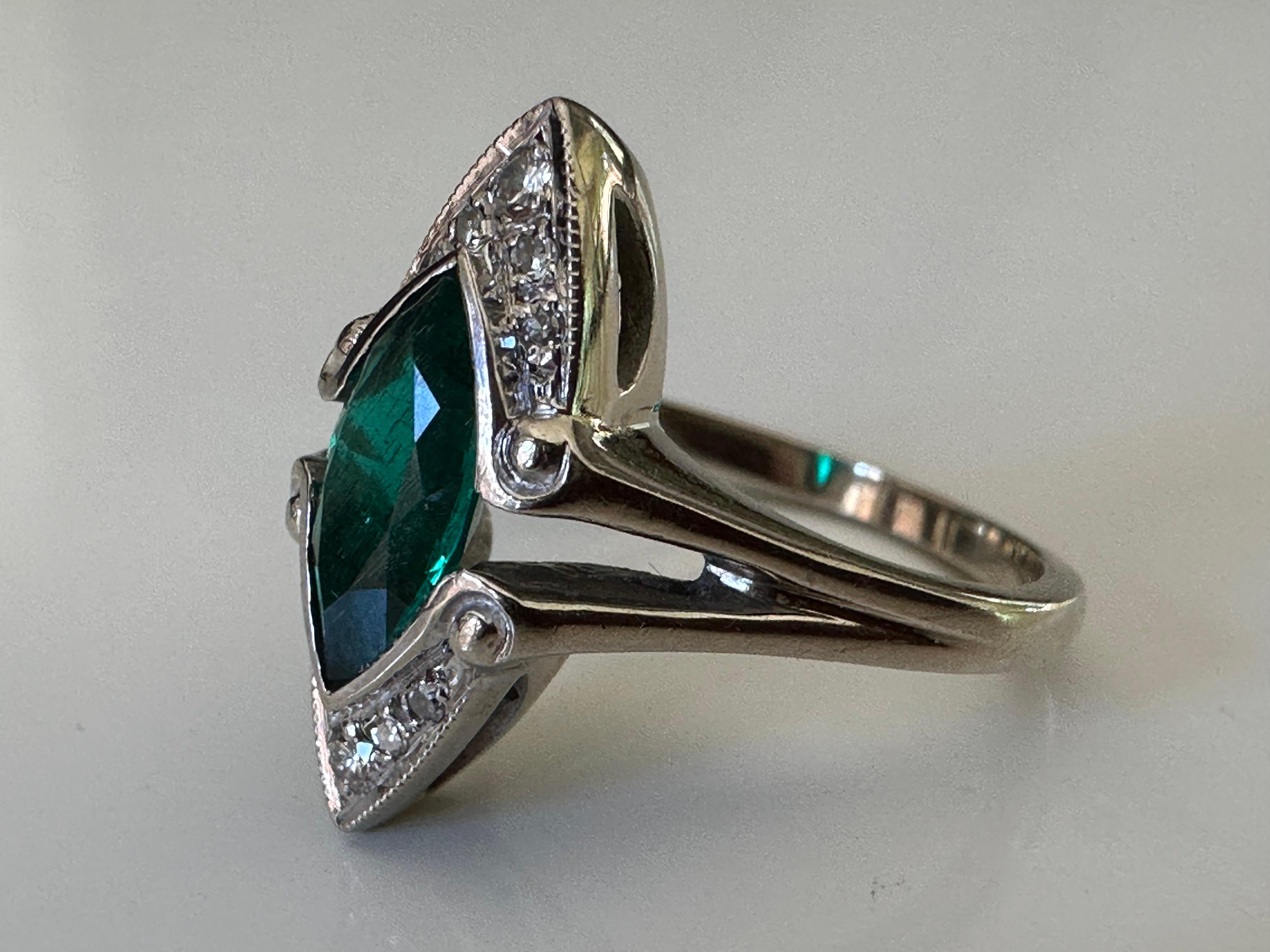Crafted in the 1940s, this retro ring features an approximately 1.00-carat marquise-cut natural green emerald center stone surrounded by ten single cut and Old European cut diamonds totaling approximately 0.15 carats in a navette-shaped setting with