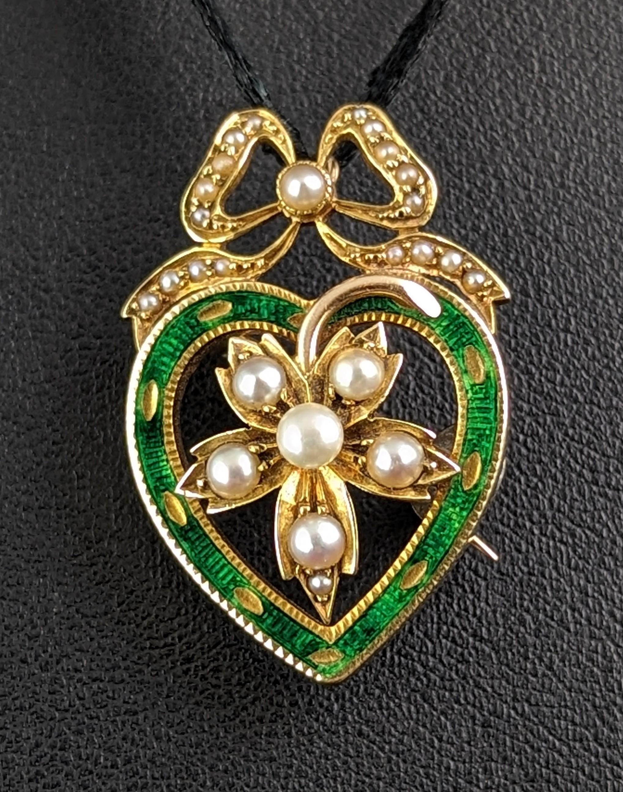 This antique Green Enamel and Pearl Heart pendant brooch is simply divine.

A beautifully designed piece it is crafted in 9ct yellow gold in a heart shape with a bow design top and a pearl adorned leaf to the centre.

The heart is decorated with a