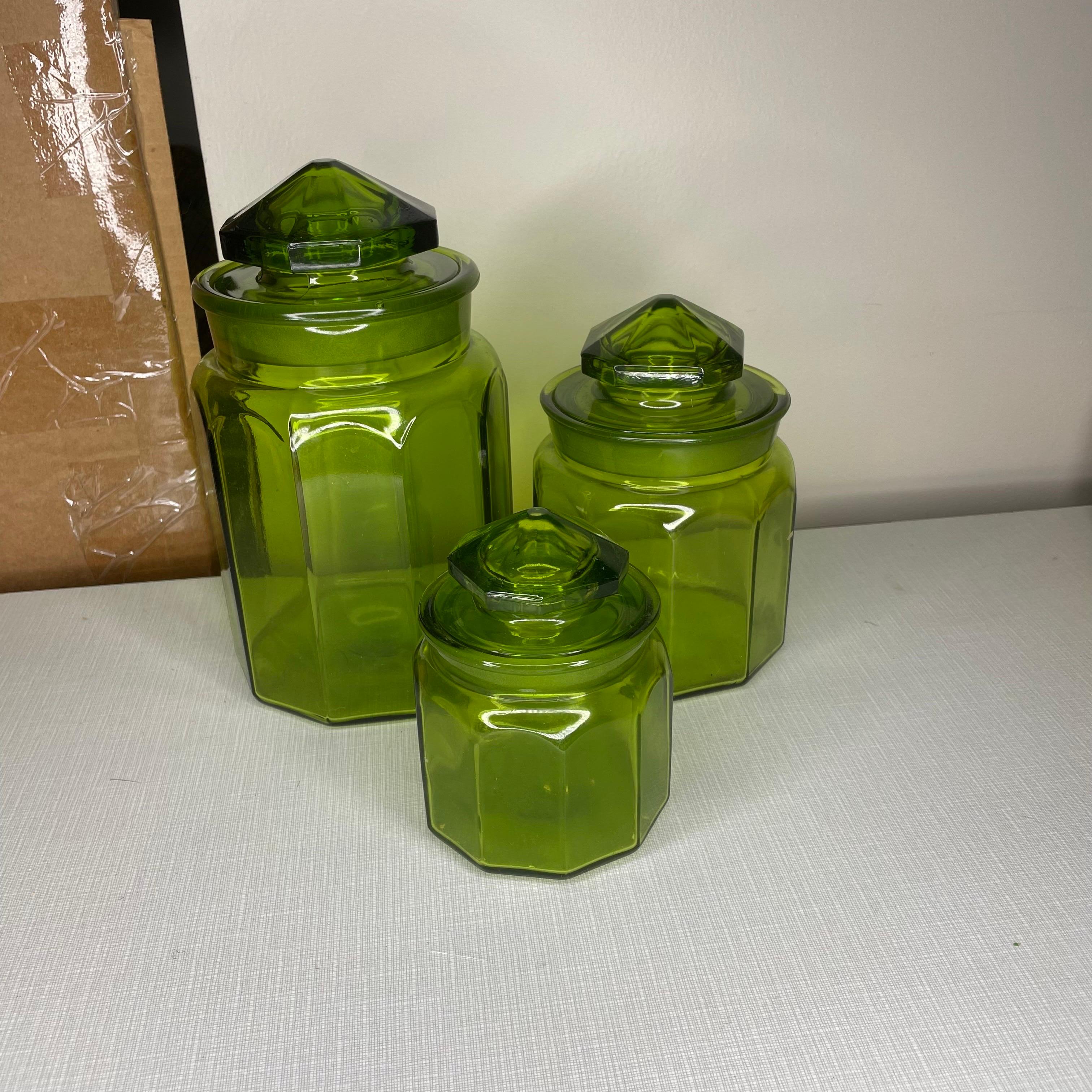 Set of three antique green glass canisters. Measurements are 9 1/2 inches for the tall one by 5 inches in diameter; the medium one is 6 1/2 inches tall by 4 1/2inches in diameter; The small one is 5 inches tall by 4 inches in diameter. All are in
