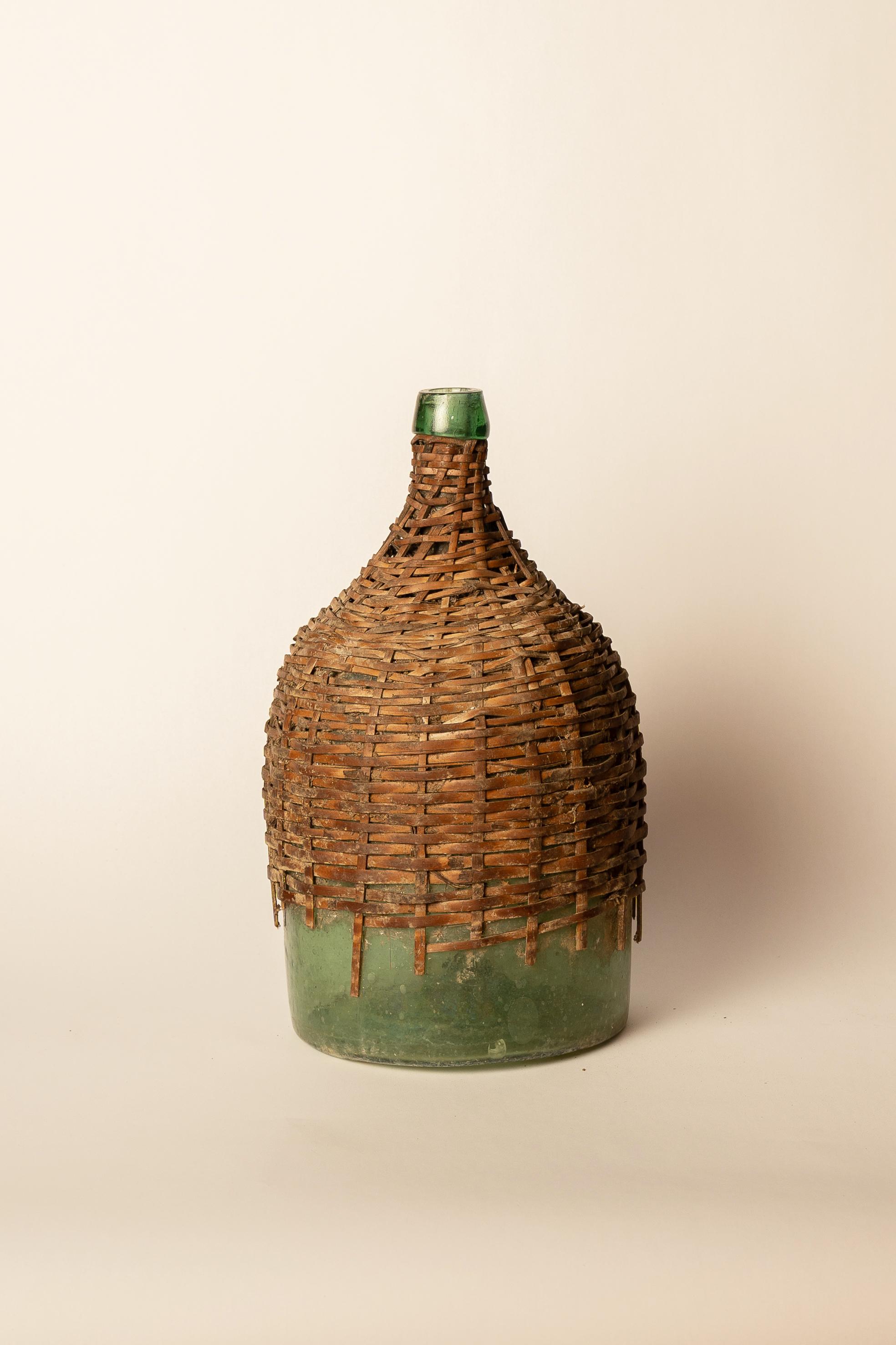 Antique Green Glass Carboy with Wicker Cover
Carboys were often protected from shocks and temperature changes by being placed in wicker covers. Very well-preserved.

Origin: Central Mexico
Period: Late XIX Century
Height: 34cm
Diameter: 18cm
