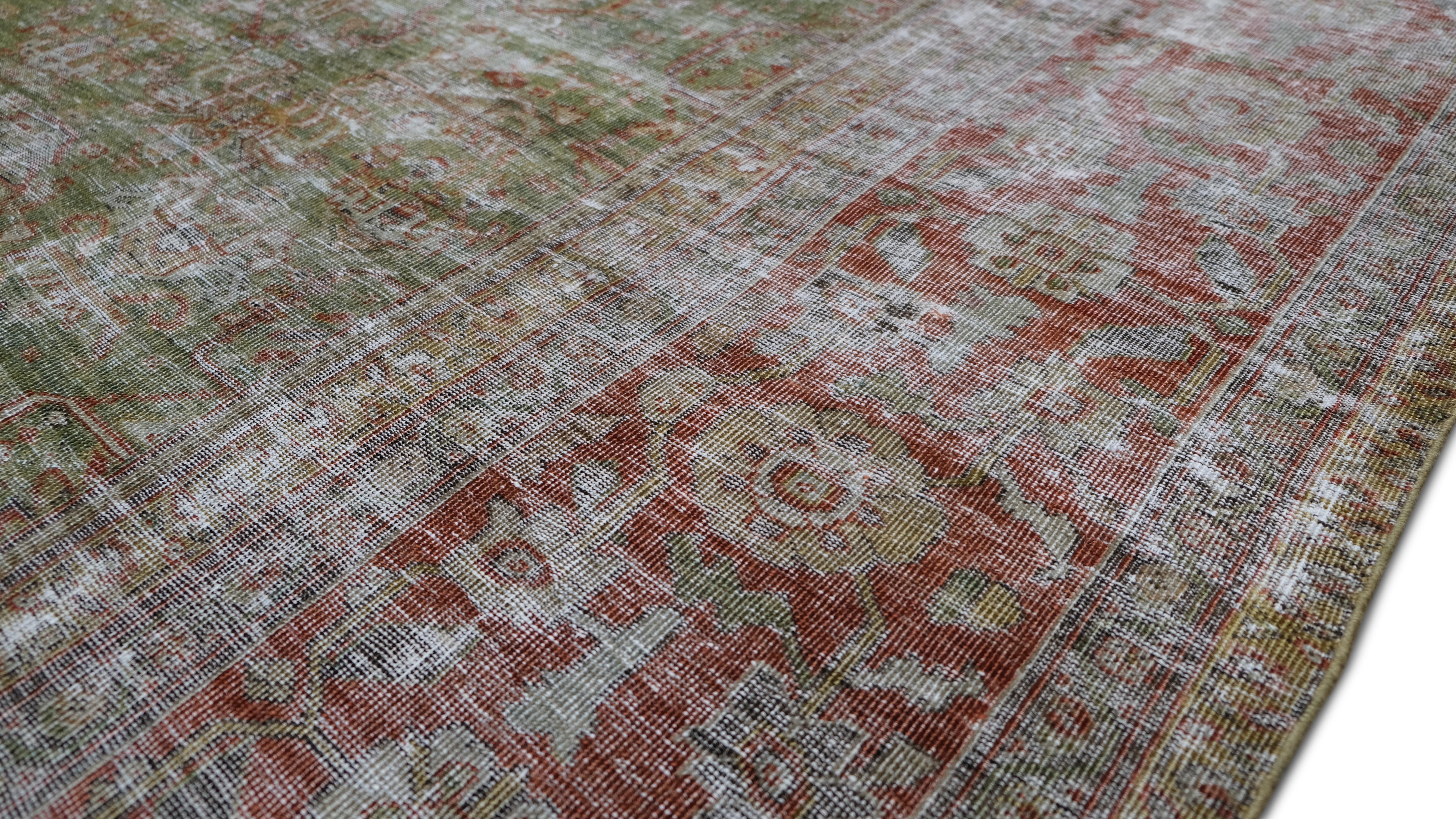 Infuse your space with the timeless elegance of this Antique wool rug, featuring a beautifully distressed floral border and intricate patterning. The muted green and red hues, softened with natural distressing, evoke an aged, vintage aesthetic
