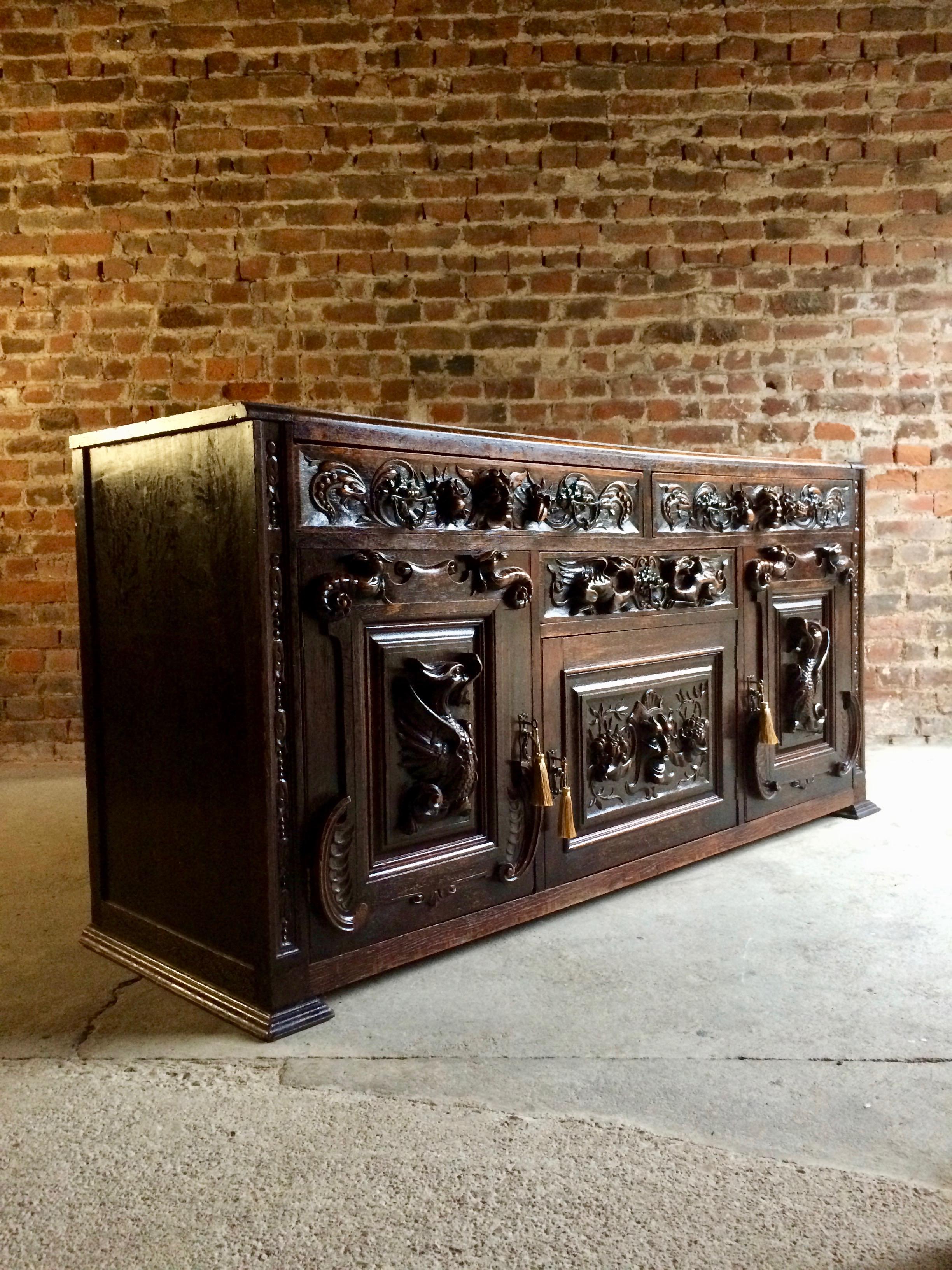 A beautiful 19th century profusely carved oak 'Green Man' sideboard circa 1890, the rectangular top over two frieze drawers carved with masks and fruit, above a single drawer and cupboard flanked by pair of cupboards, carved with dragons and