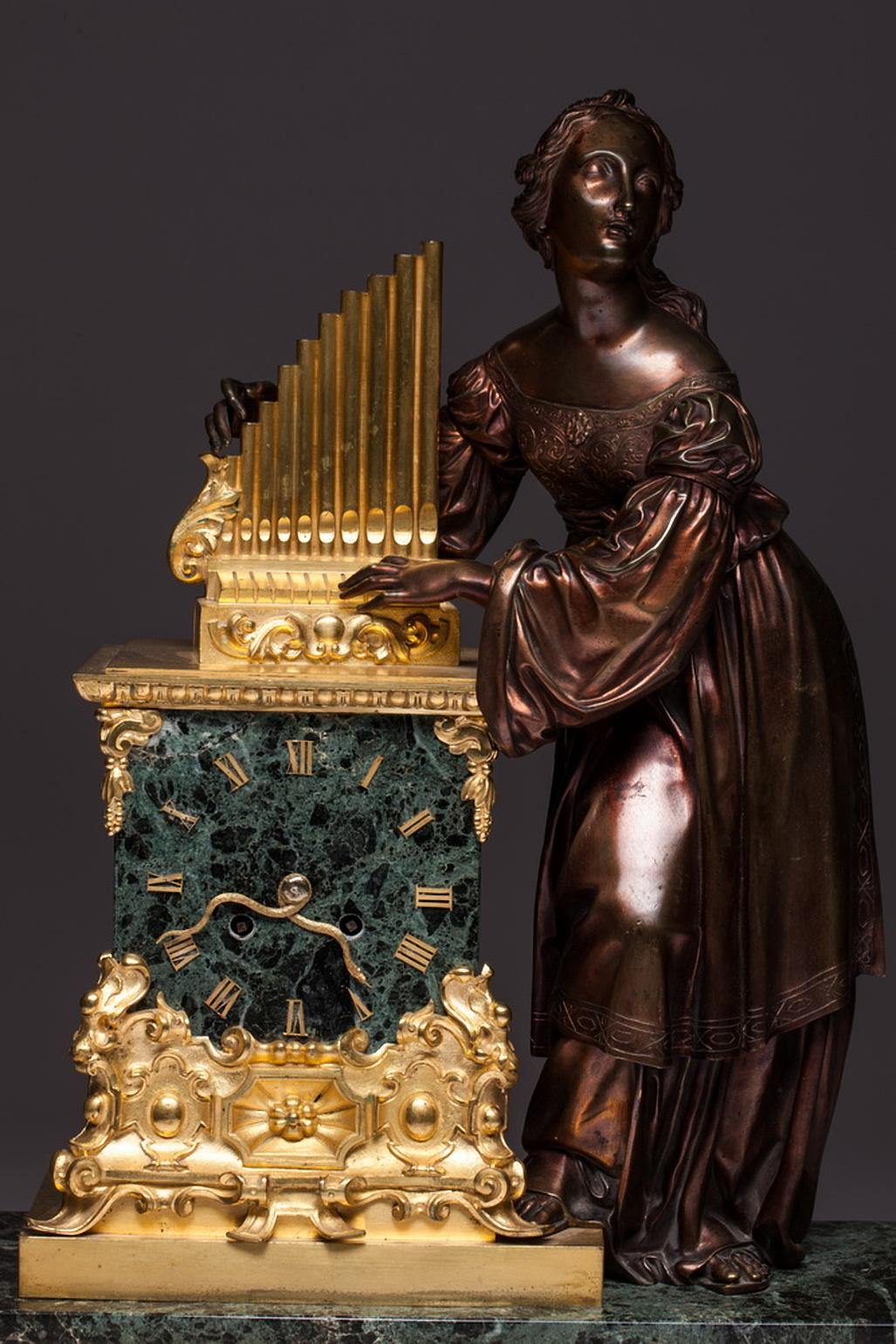 A green marble massive clock with an impressive female figure that plays with a musical instrument. Clock decorated with a lot of bronze. The most special thing is that clock mechanism arrow is like a snake. The neo-Gothic style is an architectural