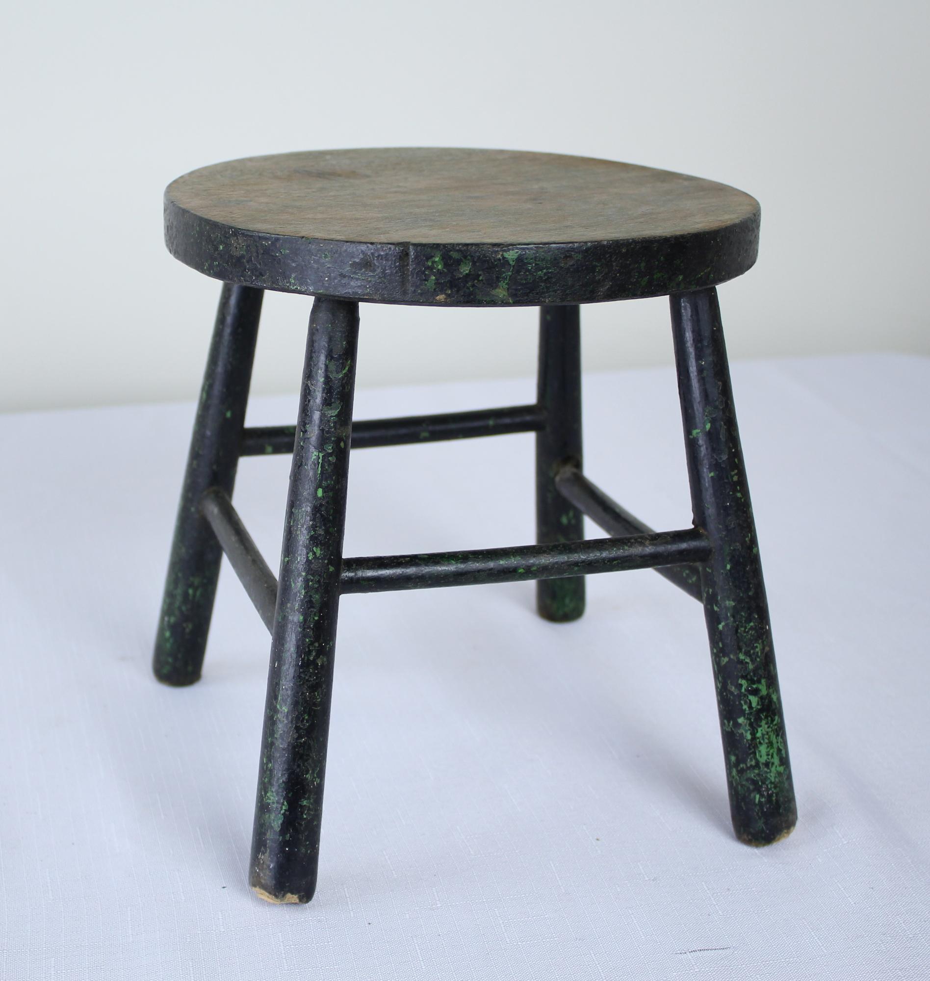 A small four-legged stool with its original distressed green paint. While this small piece used to make its home in the barn, it would be ideal as a fireside perch for a child or one's cocktail.