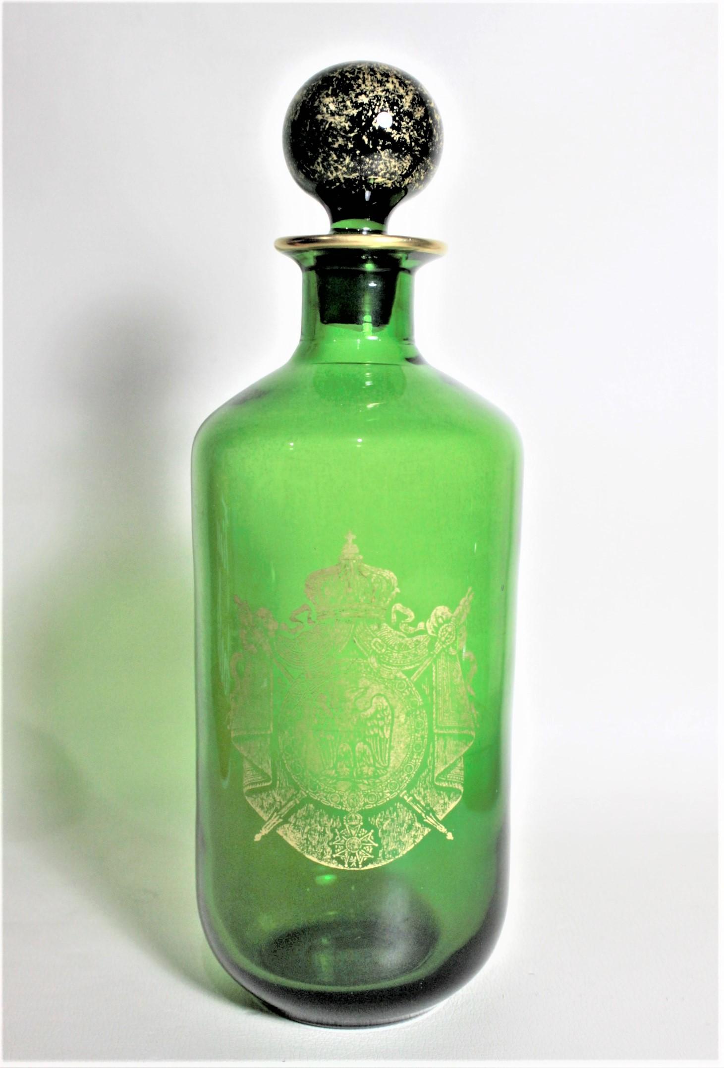 This antique liquor bottle decanter is unsigned, but was made in France in circa 1910 in the Napoleonic style. The decanter is done in a deep green glass with gold flecks in the stopper and gilt accenting around the rim. The front of the decanter