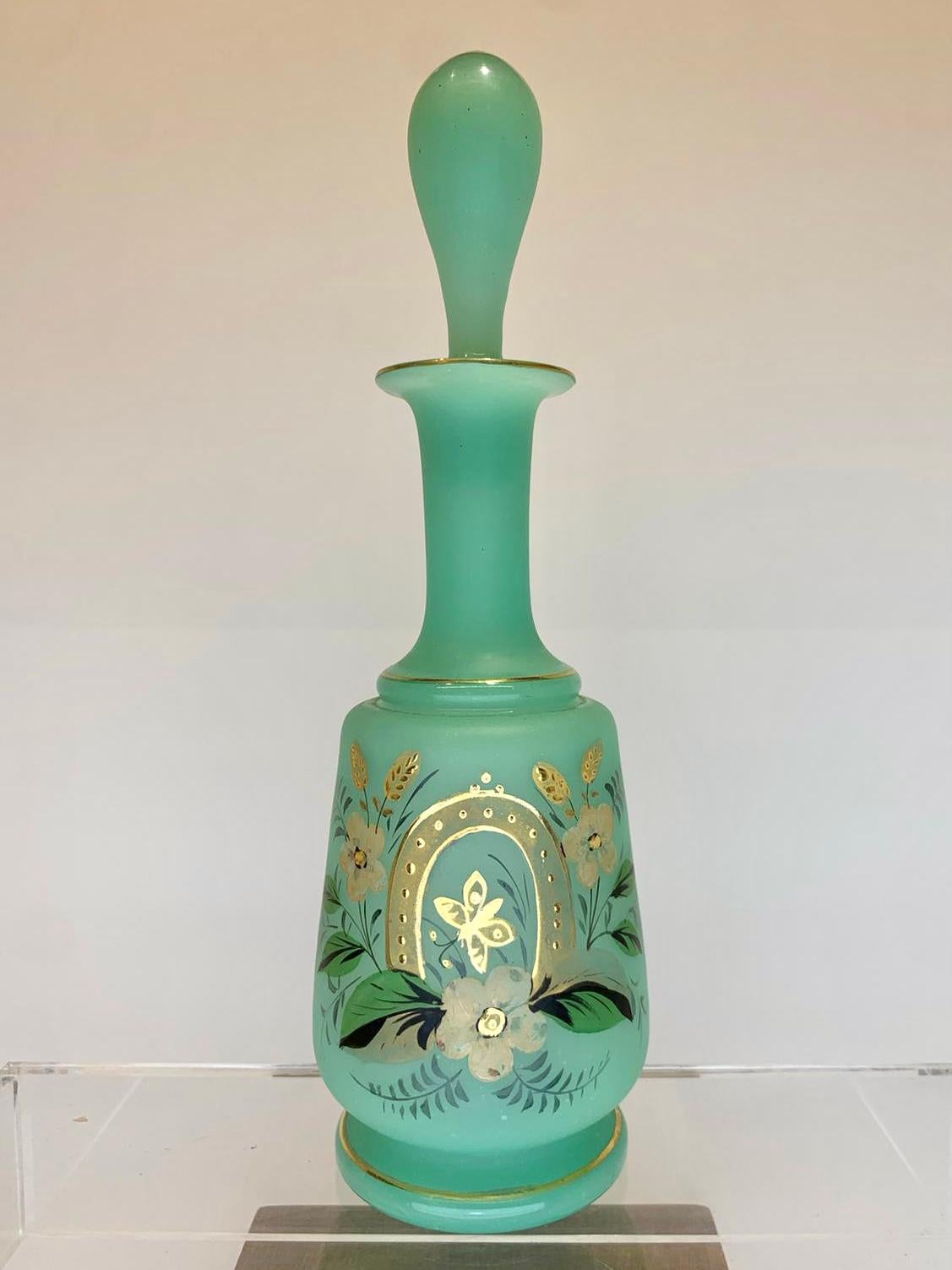 High quality perfume bottle and stopper in uranium green opaline glass with gilded enamel decoration

the circular body features colorful hand painted leaves and roses and gilding highlights

Height 25 cm.