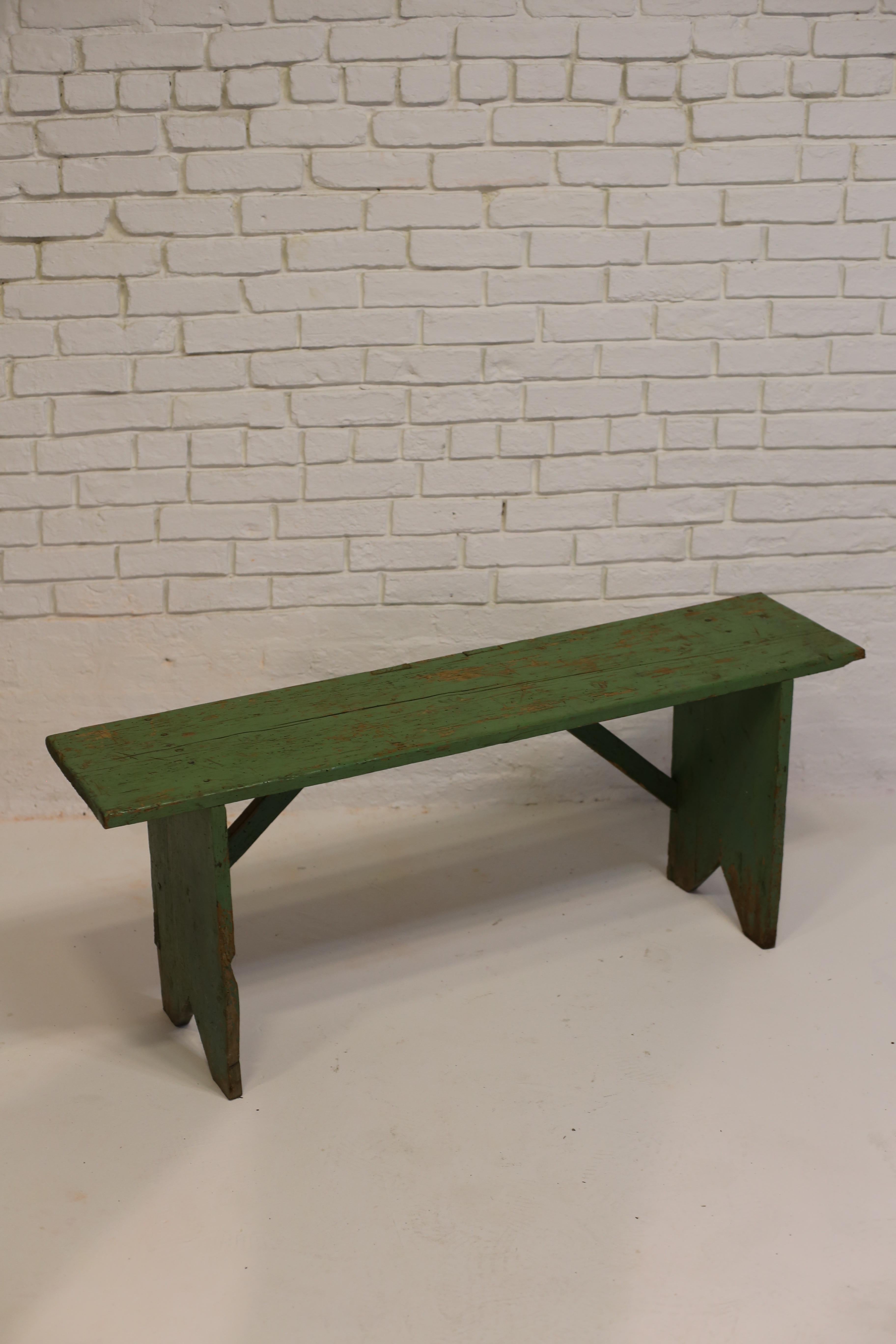 Charming green painted pine bench from the early 1900s. 

Delightful details include triangular cutouts on each foot and a pleasantly aged green paint finish. 

Bench is in solid, sturdy condition. 