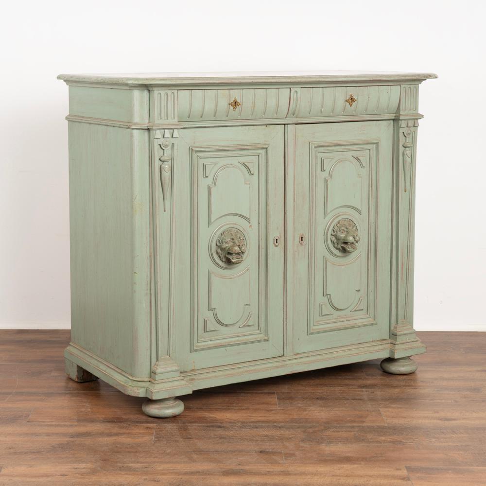 Green painted pine sideboard or buffet with carved lion head accents on doors.
Newer, professionally applied seafoam green paint brings fresh life to this cabinet from the late 1800's.
Note the handsome carved panels, dentil molding and attractive