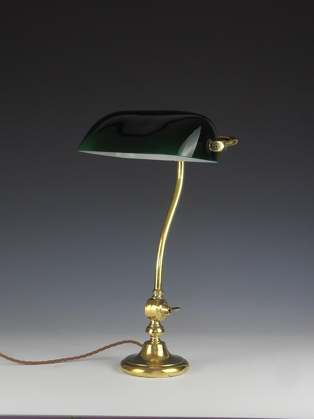 A stunning Greenalite bankers lamp in brass.

The shade is a lovely hue of dark green glass and white inside, has two small chips

The base allows for a very small amount of adjustment (not much, however, due to the weight of the glass) and is