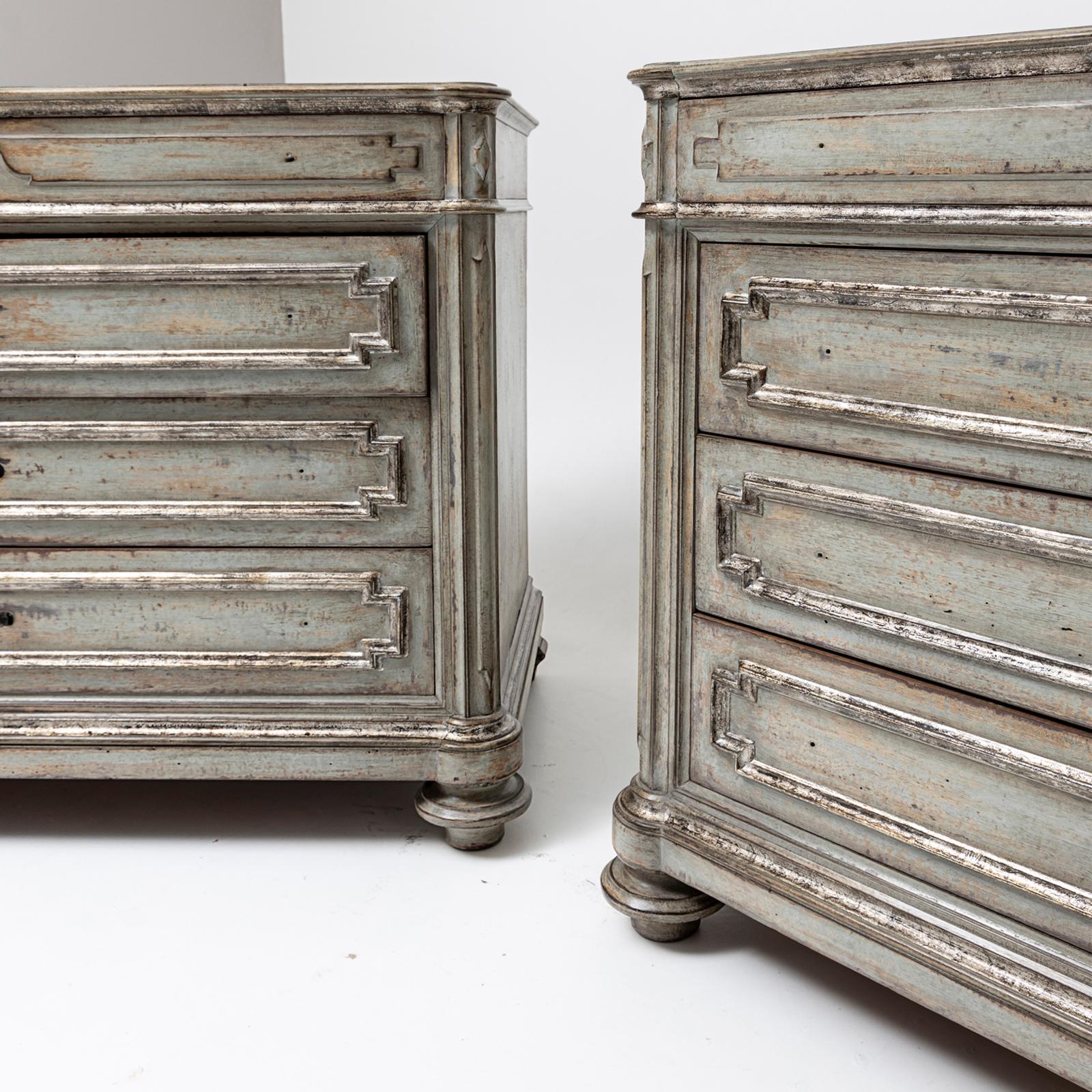 Large pair of chests of drawers with embedded white marble tops and four drawers as well as carved details. The chests are refinished in a soft, distressed gray paint that highlights their antique character and craftsmanship. The slightly worn look