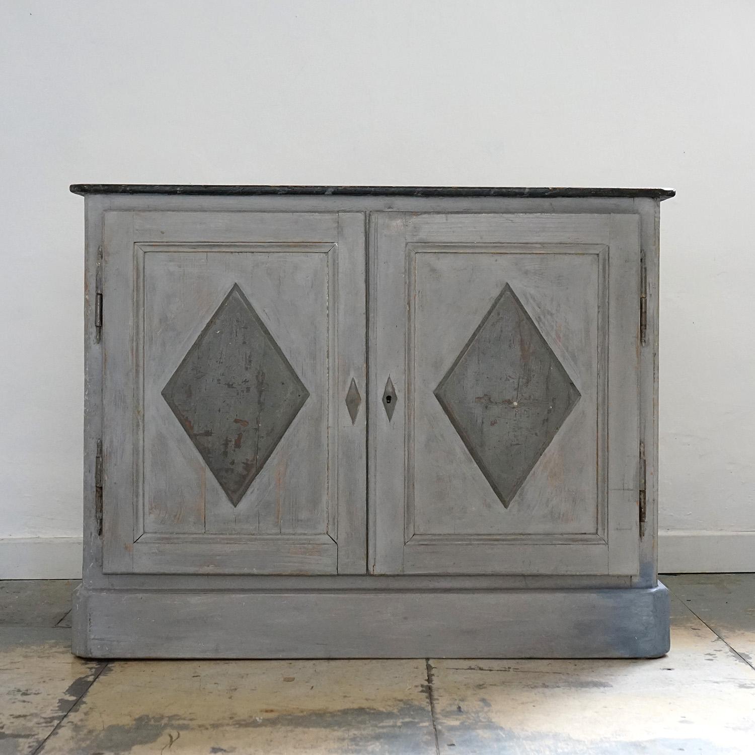 ANTIQUE LOW CUPBOARD.
A darker grey painted top above a mid-grey carved lozenge-shaped panelled doors on a light, almost silvery grey ground.
 
A removable internal shelf.
 
It is in good vintage condition and is structurally sound, there is some
