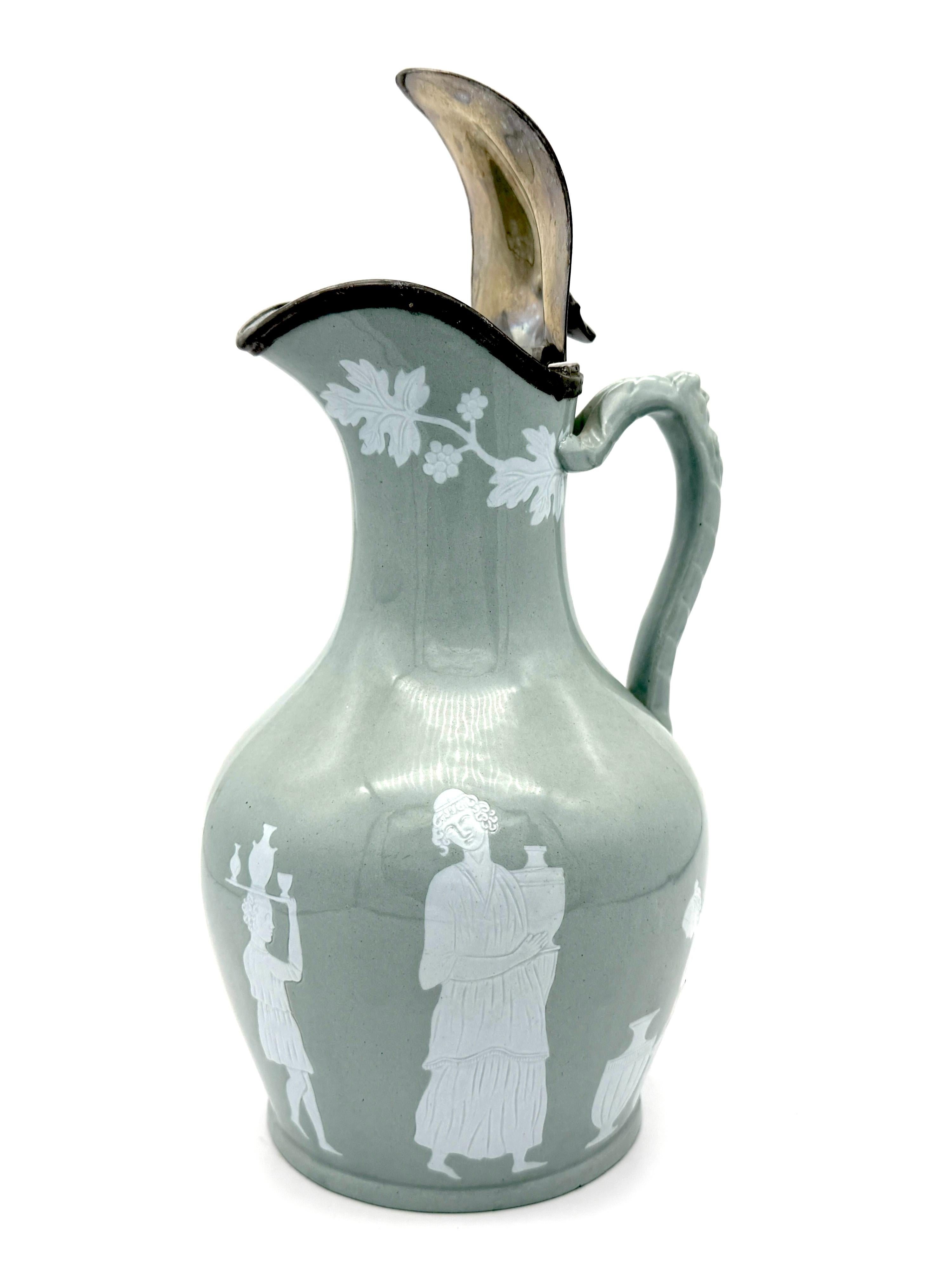 This elegant  grey and white stoneware pitcher was created by T.&R. Boote  in England in the 1840's. The pitcher is made out of light grey stoneware and fitted with a hinged metal lid. The lid carries the signature Nixon &Sons.
It is decorated with