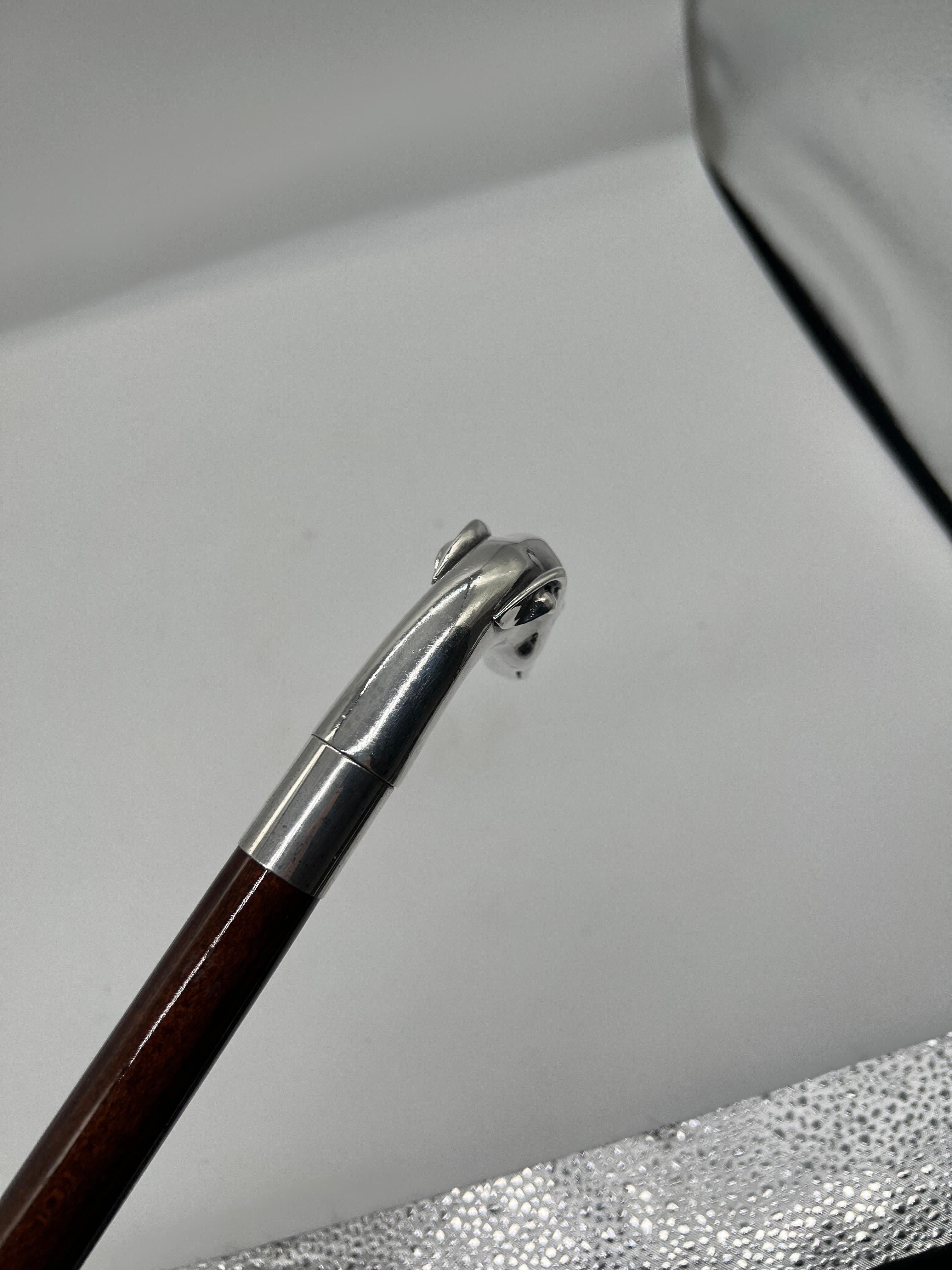 A walking stick or cane, likely 20th century. The handle features a greyhound head cast in sterling silver which is affixed to a mahogany shaft and terminating to a brass tip. Marked to handle with makers mark and 925 sterling content.