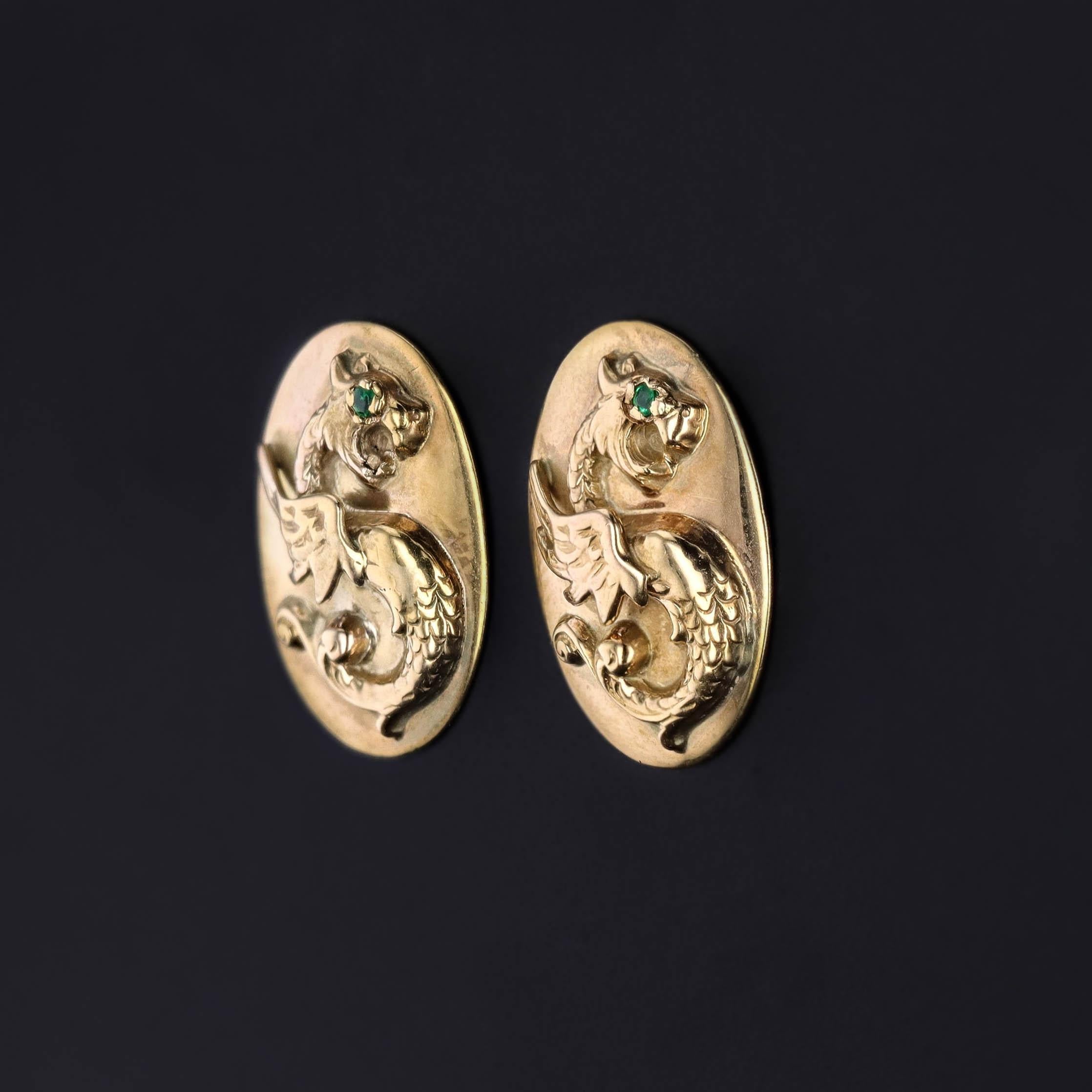 A captivating blend of history and modern wearability, this striking pair of 14K gold earrings features mythical griffins, their fierce expressions brought to life with vibrant emerald eyes. These bold, sculptural creatures—symbols of strength and
