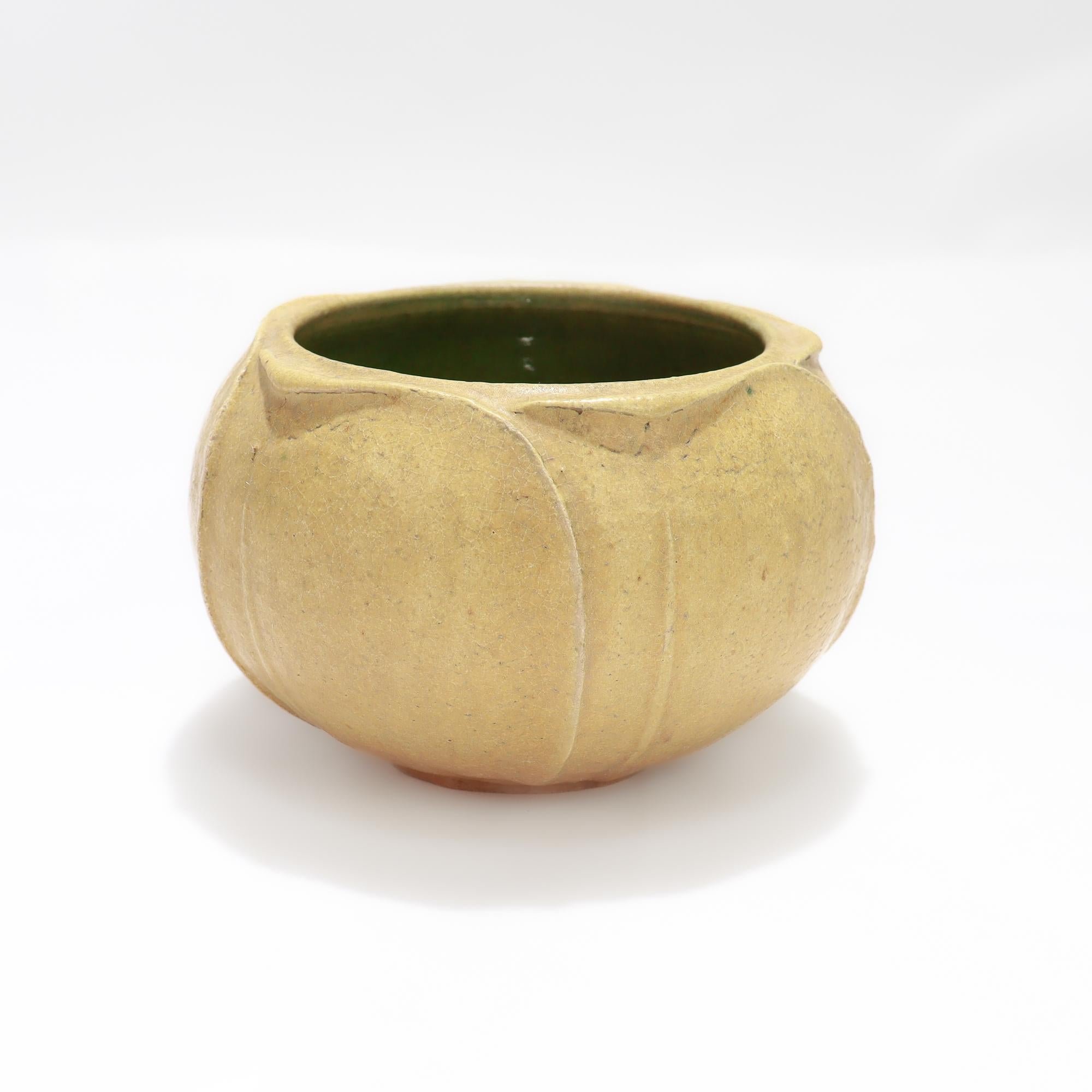 A fine antique American Arts & Crafts vase or bowl.

By Grueby.

With a mustard yellow matte glaze to the exterior and a glossy green to the interior.

In a squat form with 5 overlapping leaves or stylized flower petals to the exterior.

The form