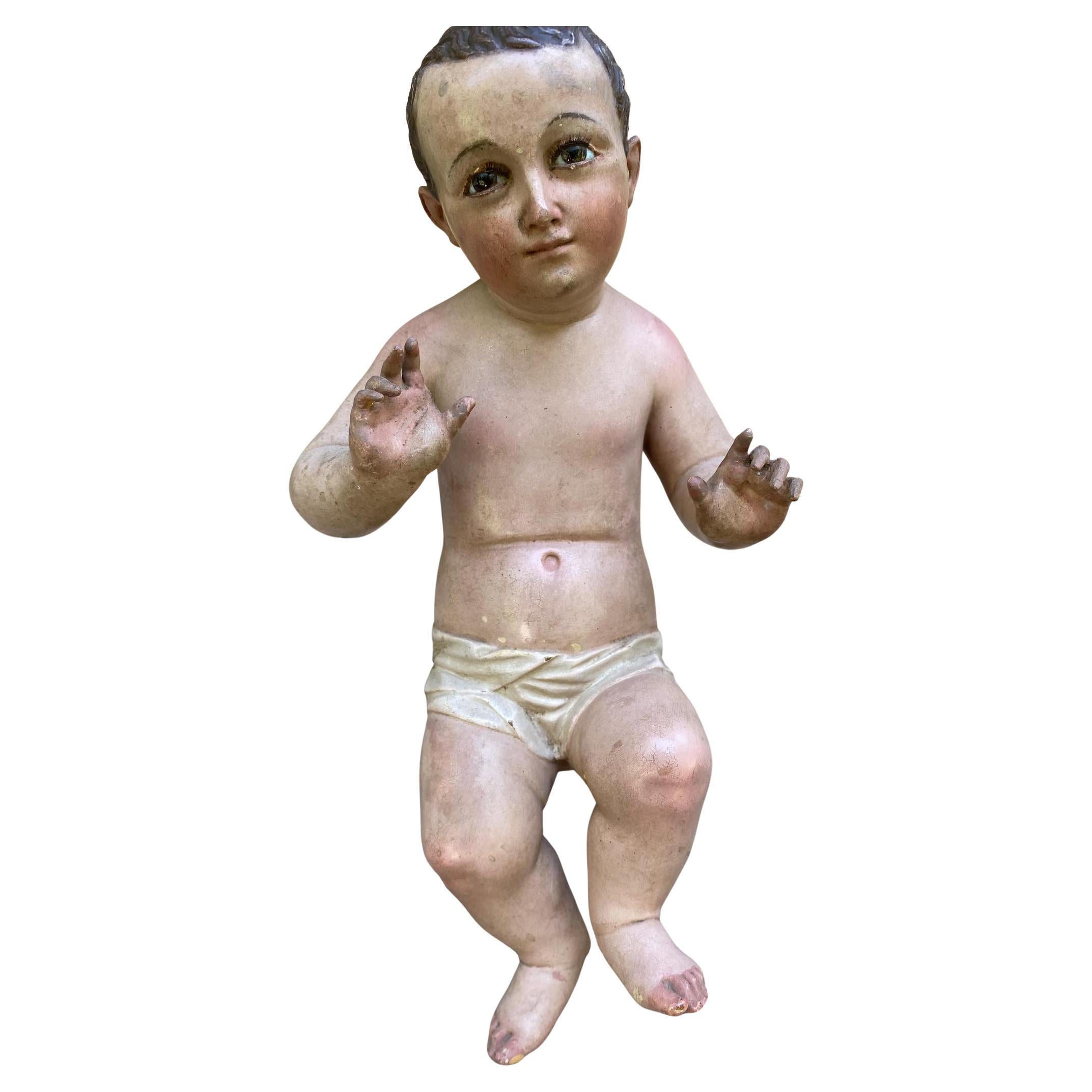Figura di Santo Niño policroma
XIX secolo, Guatemala.
Figura in legno intagliato e policromato del Bambino Gesù, raffigurato con tratti delicati e un'espressione naturalistica. Il bambino è raffigurato in una posa seduta/alzata, con le mani alzate