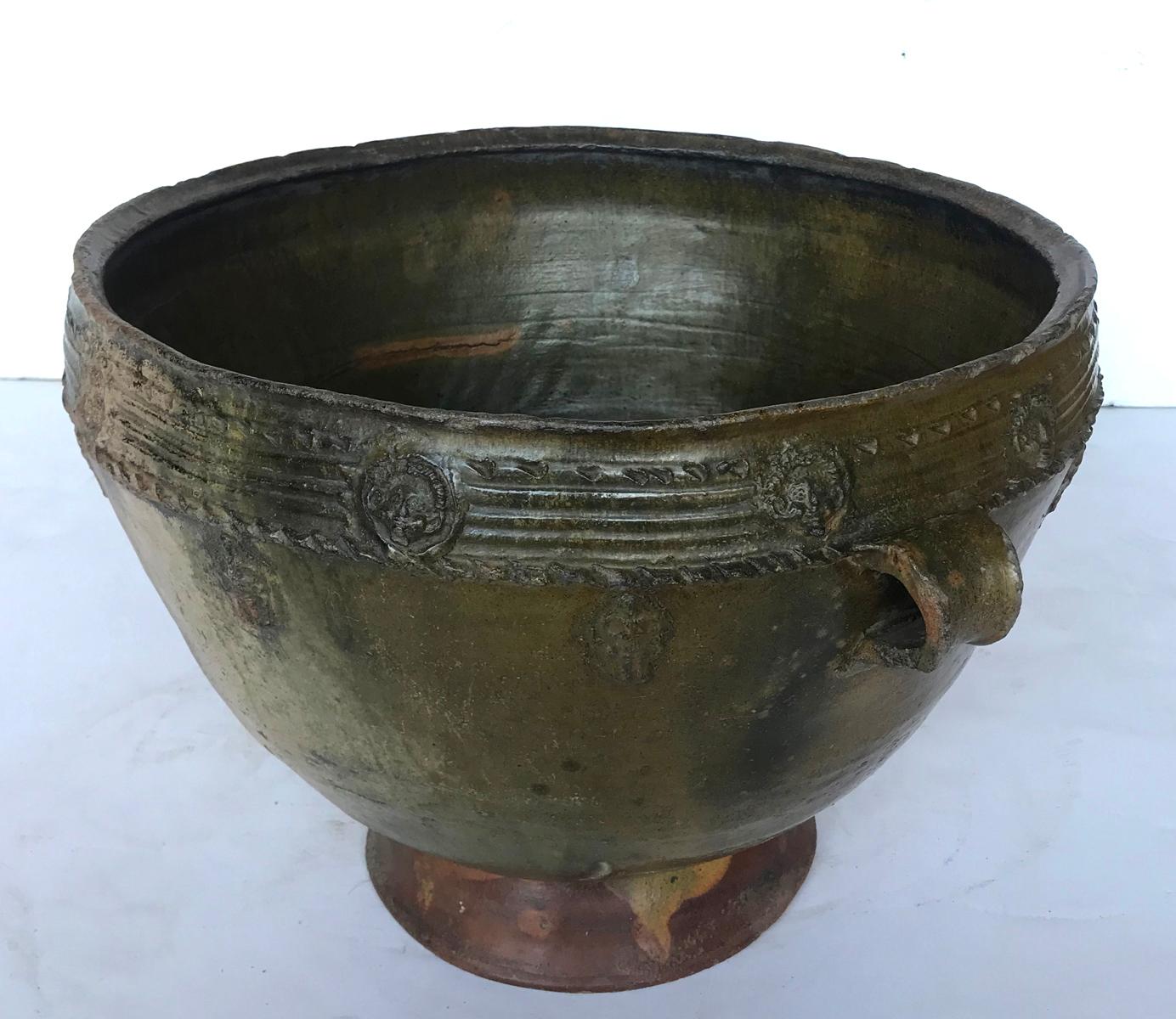 Early 20th century water pot, a Trubal,  from the highlands of Central America.   Delicate applied pottery decorations of women and faces surround the outer edge. Handmade, wood fired, resulting in a lovely greenish, earthy glaze.
Sturdy and
