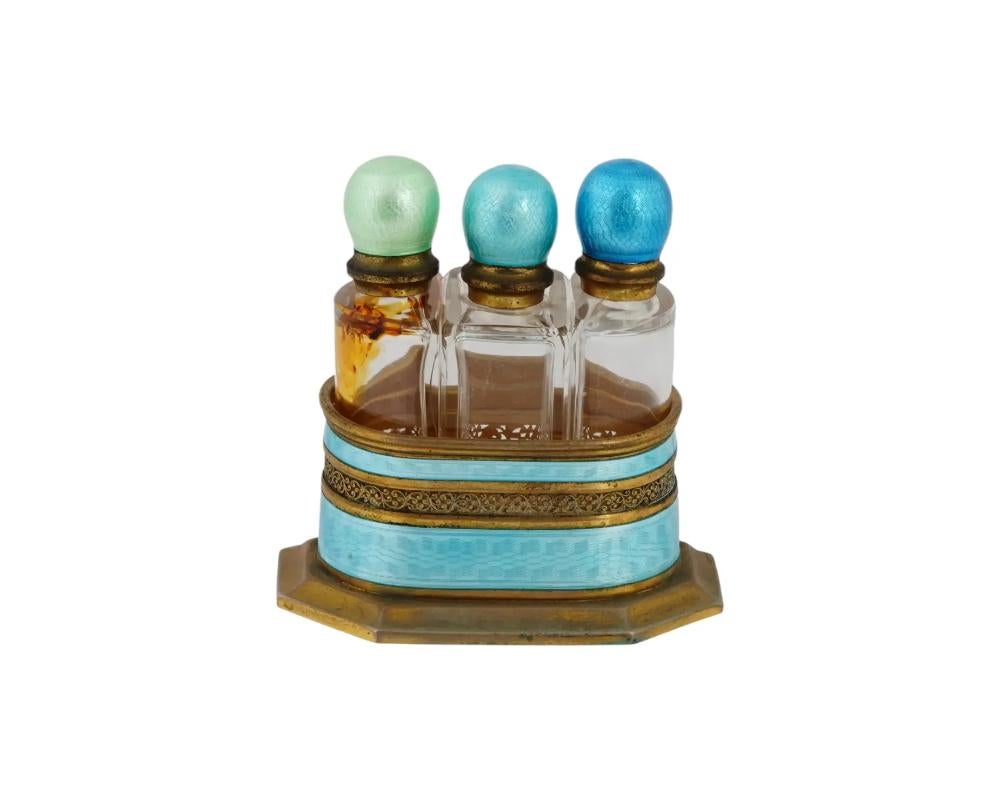 An antique set of three perfume bottles with caddy. Gilt silver stand with turquoise blue guilloche enamel decor and pierced ornamental band. The clear glass bottles have guilloche enamel lids of individual color tone. Unmarked. Perfume Cluster,