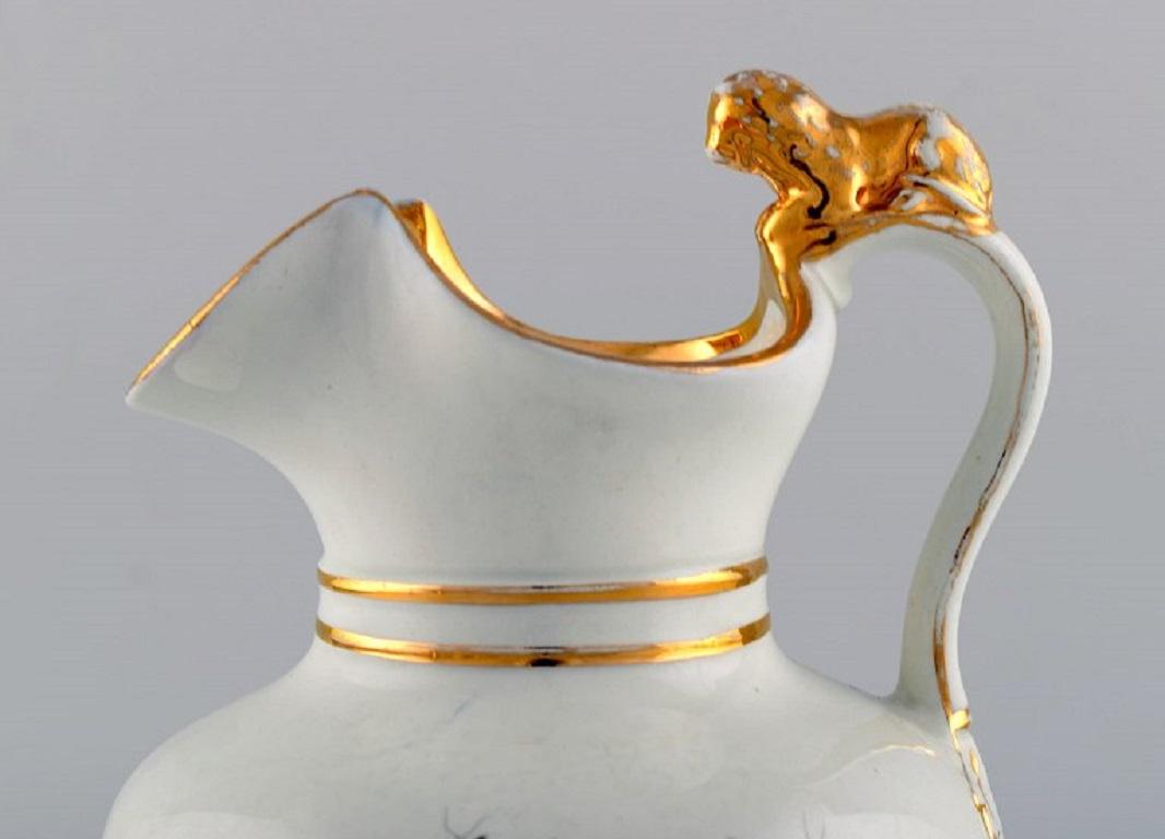 Ancienne carafe à chocolat Gustafsberg en porcelaine avec un lion sur l'anse. 
Fleurs peintes à la main et décoration dorée. Fin du 19e siècle.
Mesures : 24 x 16 cm.
En bon état d'origine. Usure normale sans éclats ni fissures.
Estampillé.