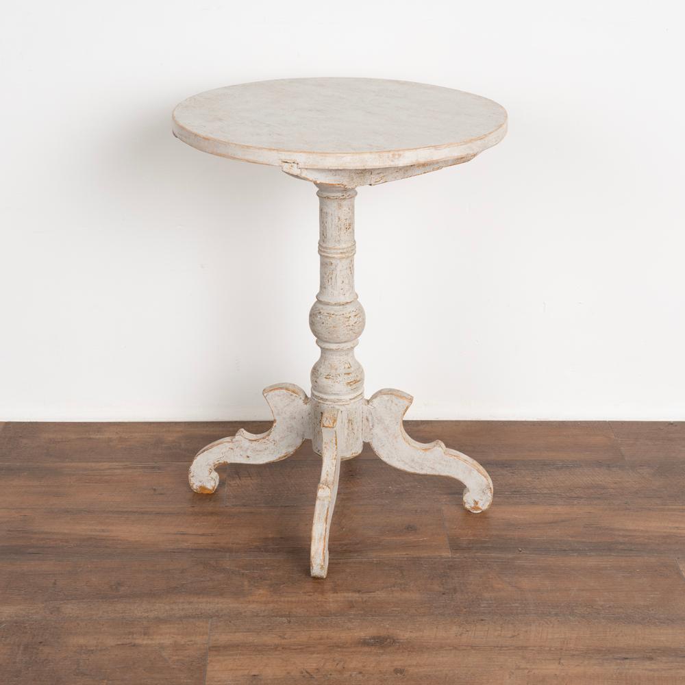 Antique Swedish gustavian tri-foot turned pedestal side table.
Later applied professional white painted layered finish, lightly distressed to fit the age and grace of this Swedish country table.
This side table may also be used as a nightstand,