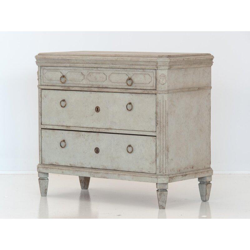 An early 20th century pair of Swedish Gustavian style chests of drawers. Each commode has three drawers with brass ring pulls and escutcheons. Top drawer has four beautifully carved lozenges. Canted corner with medallions and reeded detail on the