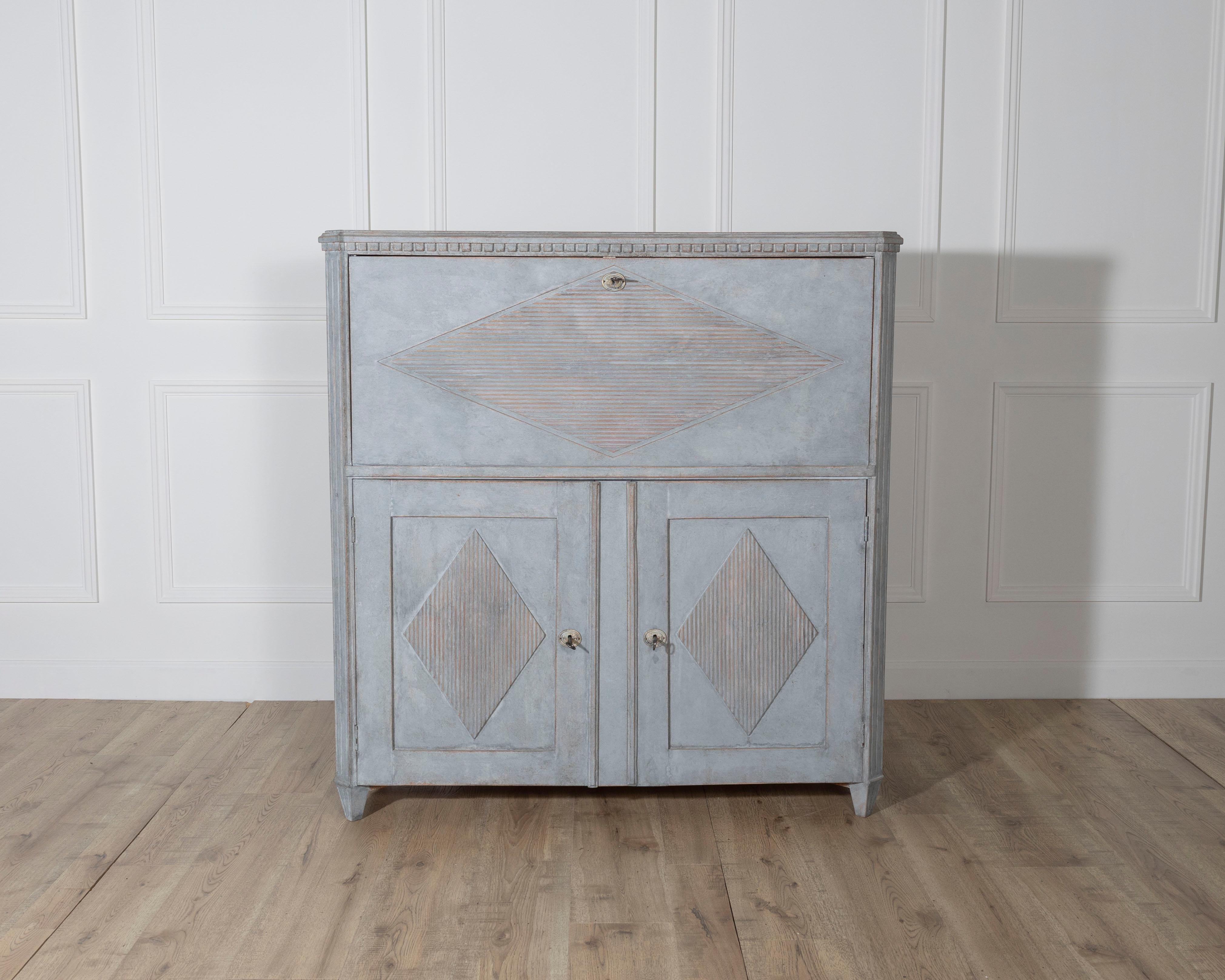 An elegant mid-19th century Gustavian style bureau, circa 1840–1850, painted in a soft blue with interior details in antique white. The upper section functions as a secretary, enclosed by a fall-front flap decorated with a centrally positioned