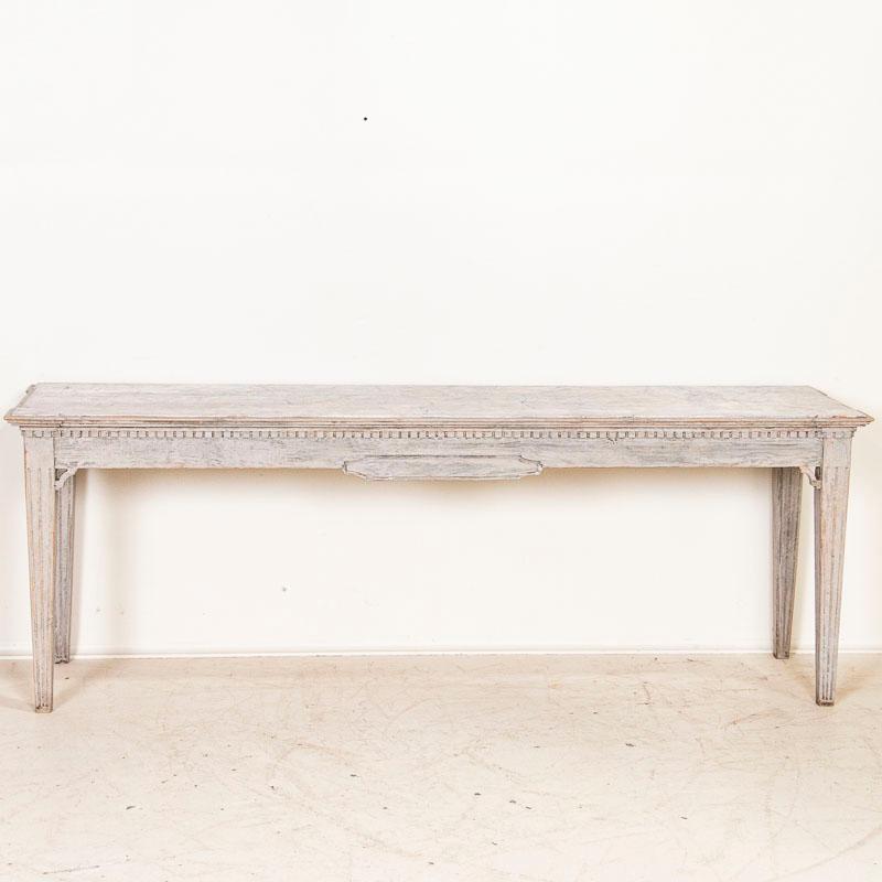 Lovely lines accentuate the gustavian style of this Swedish console table. Note the fluted legs, dentil molding along the top trim and simple corner accents. The soft gray painted finish (newer) with faux marbling top fit the style well. This