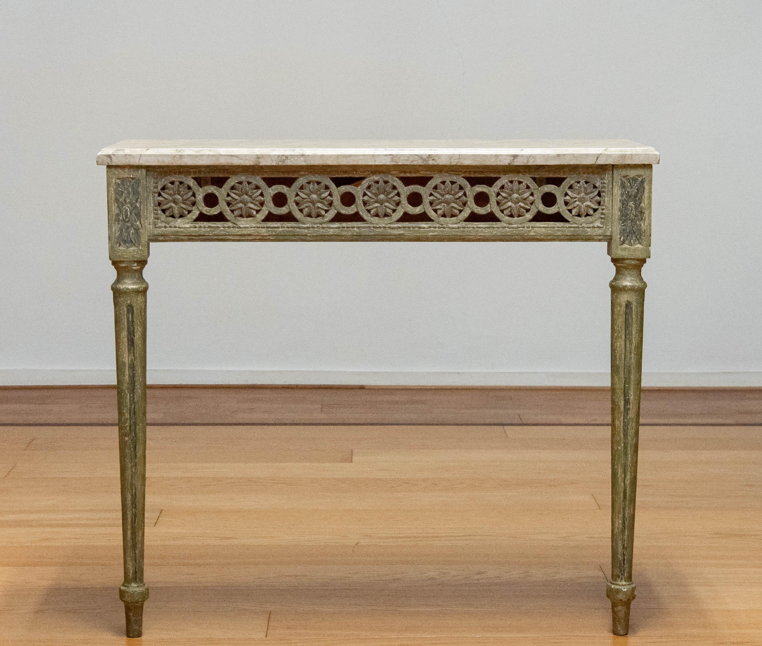 Assolutamente bella e decorativa console antica svedese di Lous XVI intagliata e dipinta a mano, inizio XVIII secolo. Il grembiule aperto in quercia è dipinto in verde con sfumature grigiastre, gli angoli in quercia presentano rosette ovali
