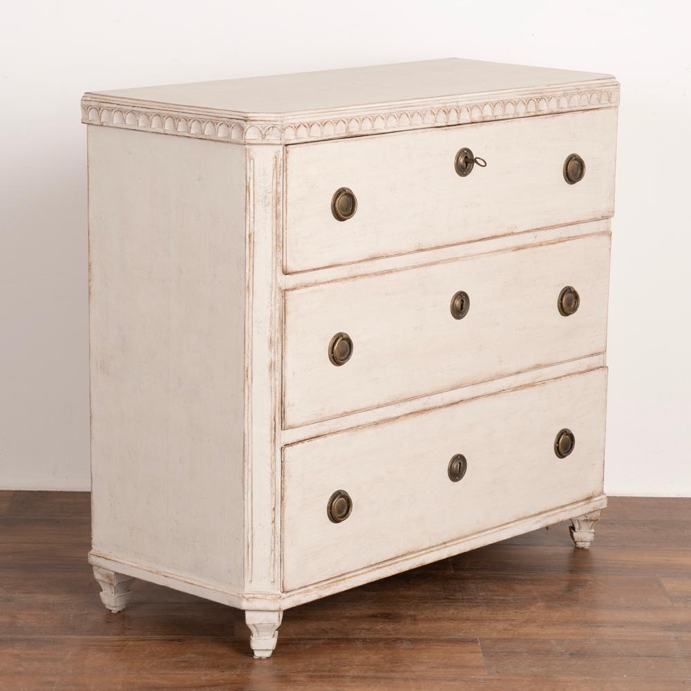Gustavian Style white painted chest of three drawers with carved detail along top.
Newer professionally applied and layered white painted finish, lightly distressed to fit age and grace of chest.
Restored, strong and stable, drawers function; top