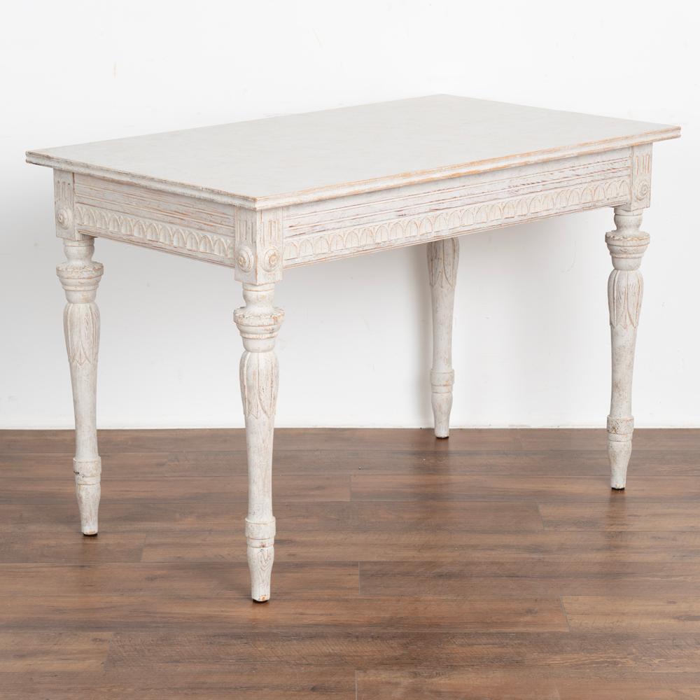 Swedish Gustavian style side table, may also be used as a small desk. 
Lovely turned and carved legs with elongated leaf motif and carved skirt with scallops add to the romantic grace of this side table.
Restored, later professionally painted in
