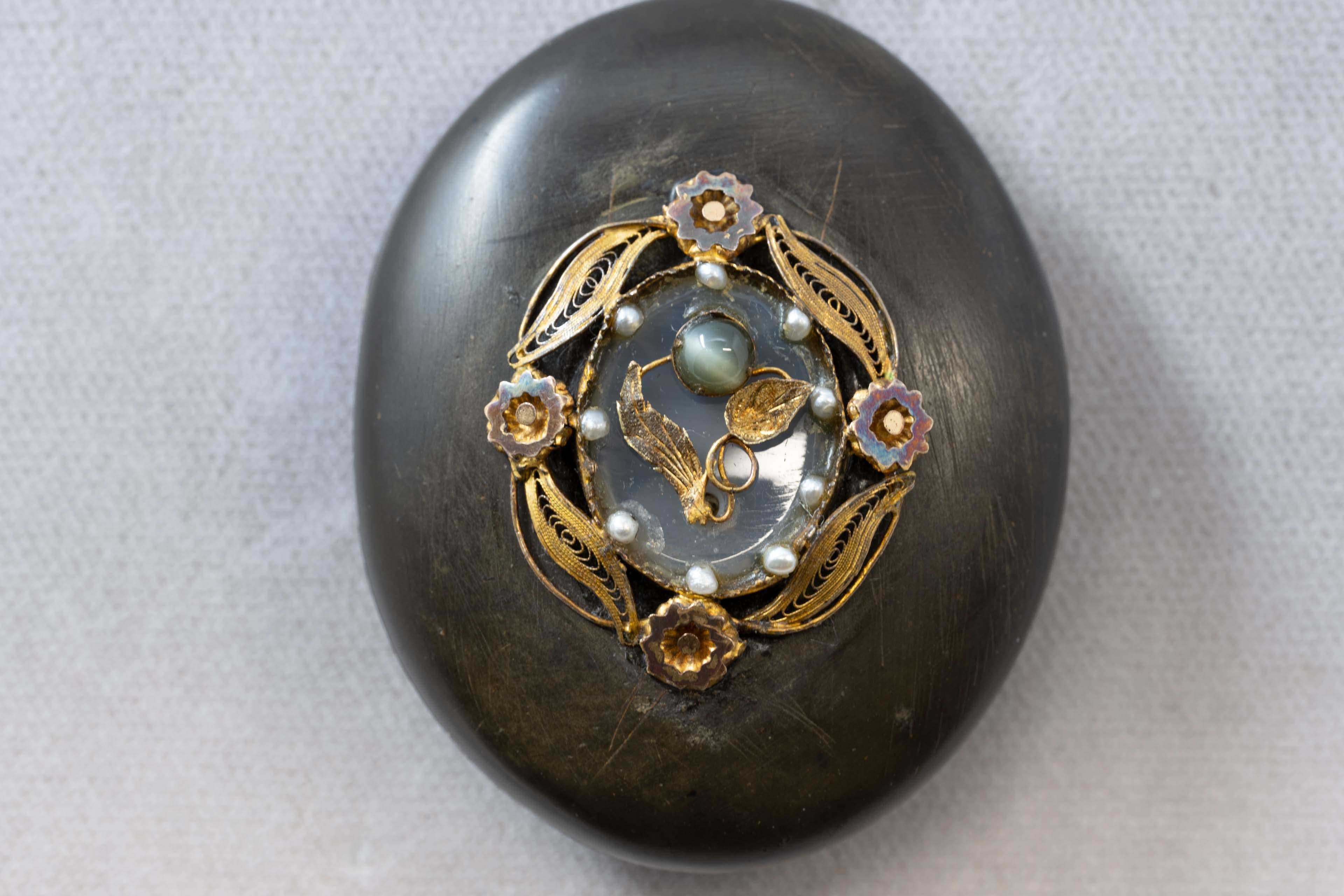 Antique Gutta Percha pendant locket decorated with rock crystal, 14k gold, sead pearls and tiger eye stone. Made mid 19th century, measures 52mm long x 41 mm wide, not marked. In good condition.
