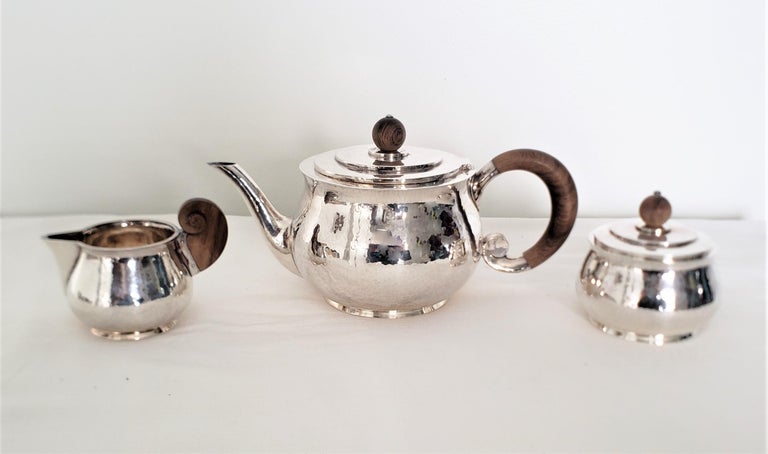 This sterling silver tea set was made by J.A. Hoeting of the Netherlands and assayed in England and dates to approximately 1920 and done in the period Art Deco style. The tea set is composed of a large teapot done in sterling silver with a hinged