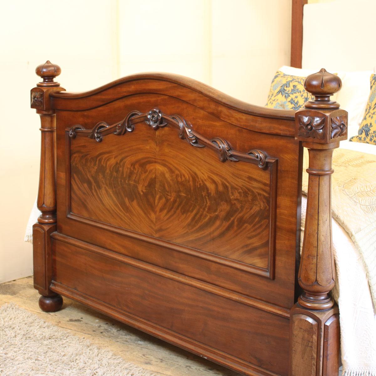 A magnificent mahogany Victorian half tester bed with flame veneer in the shaped foot panel, substantial turned front posts and tall arched canopy.
The upholstered back panel, with serpentine shape to mirror the foot panel, can be covered in a