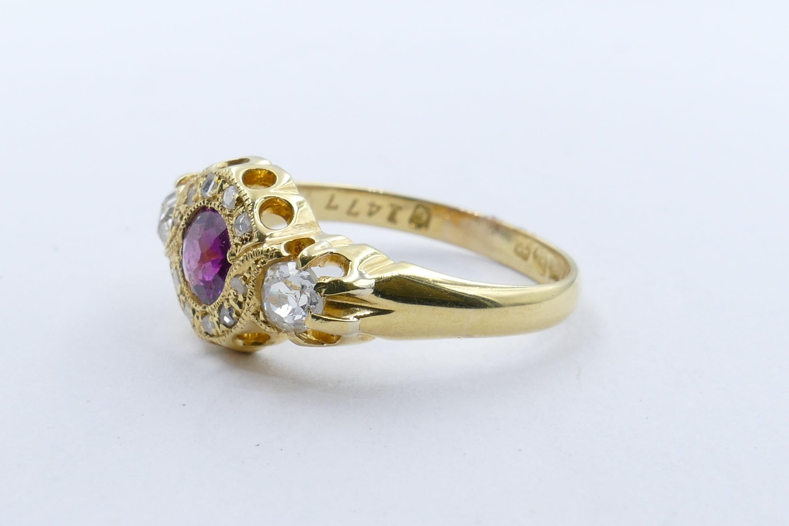 A very vibrant half carat Rhodolite Garnet is the centre feature of this beautiful old Ring, hallmarked Birmingham 1897.
The pinkish-purple Rhodolite is eye-clean, round cut, bead set with milligrain detail.
It is flanked by 2 old mine cut & a
