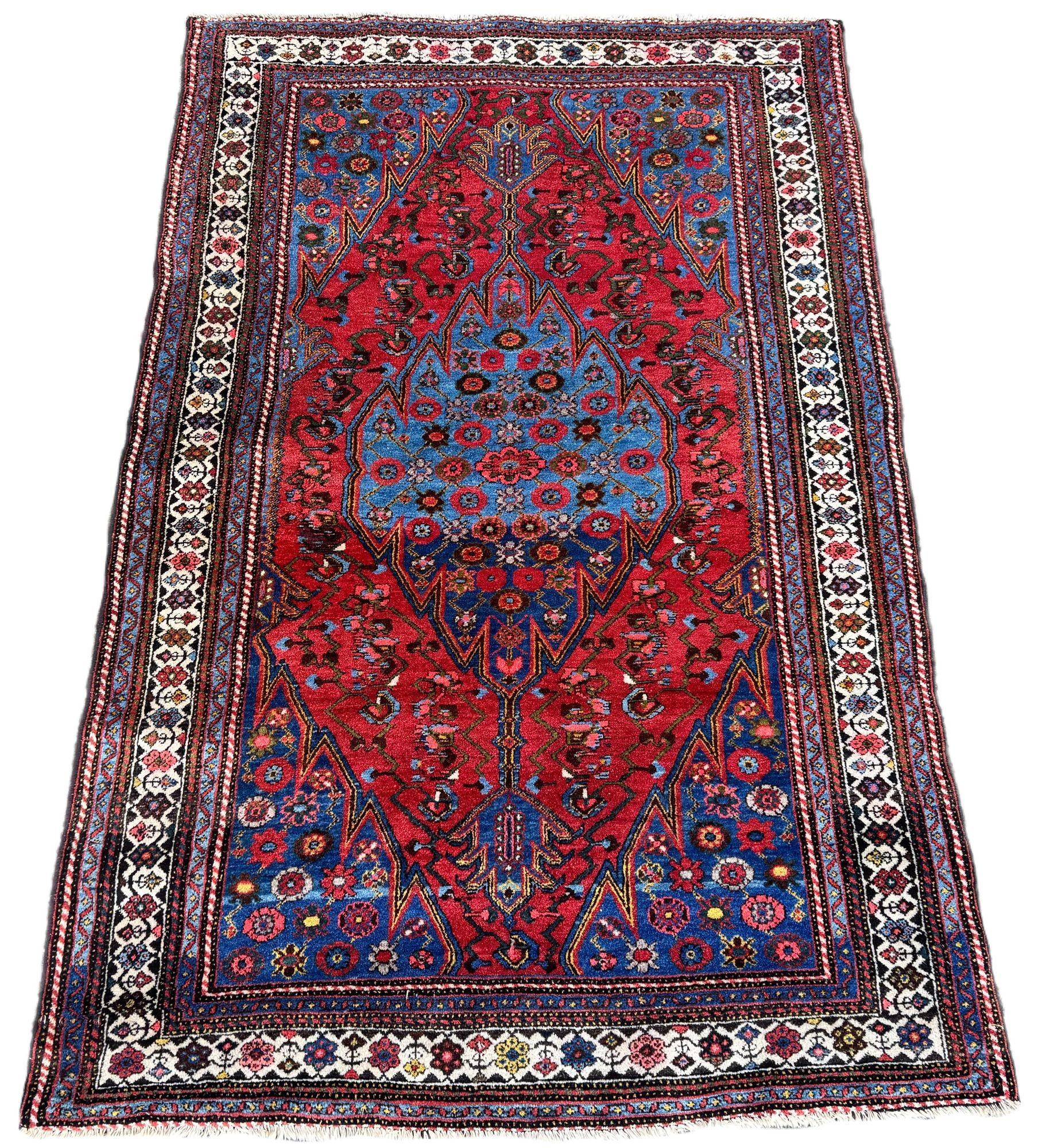 Ein wunderschöner antiker Teppich, gewebt in einem der Dörfer um Hamadan um 1920. Das Design zeigt ein indigoblaues Medaillon mit stilisierten Blumen auf einem reichen Terrakotta-Feld, das von einer hübschen elfenbeinfarbenen Bordüre umgeben ist.