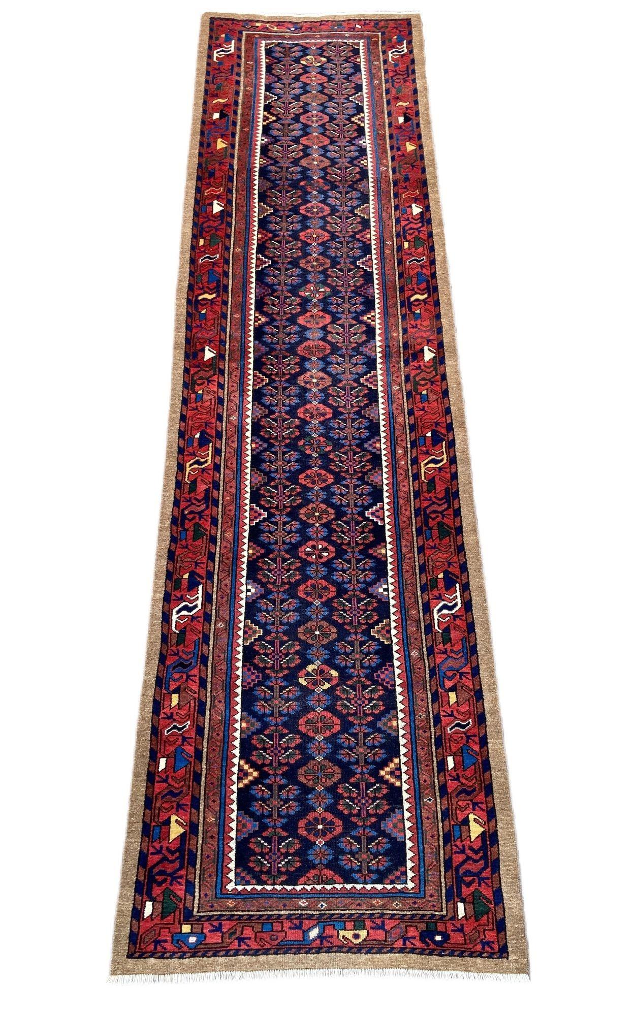 Un meraviglioso runner antico di Hamadan, tessuto a mano nella Persia occidentale intorno al 1910, con un disegno all over di fiori stilizzati su un ricco campo indaco e un bordo rosso. La qualità della lana è ottima e i colori secondari sono