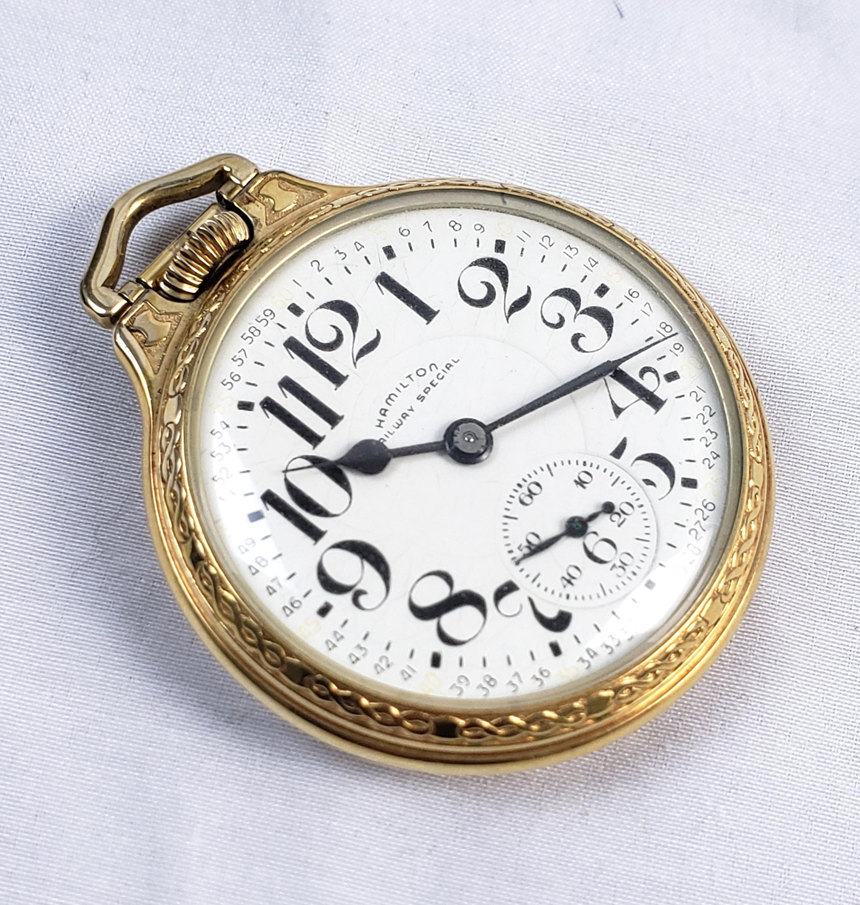 Cette montre de poche ancienne a été fabriquée par la célèbre société horlogère américaine Hamilton vers 1920. La montre est en bon état de marche avec un cadran en porcelaine blanche et de grands chiffres arabes. Le boîtier est rempli d'or et