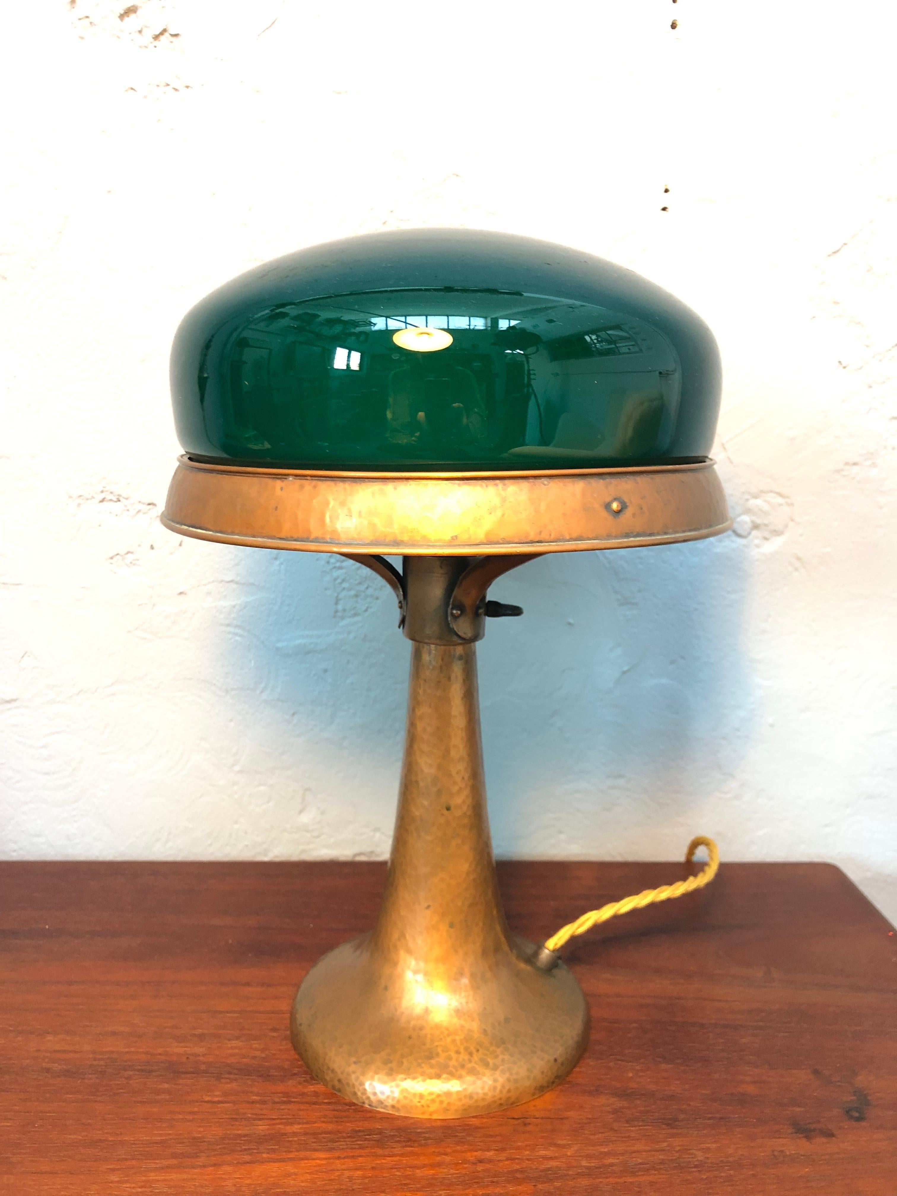 An antique hammered copper art deco Strindberg lamp from the 1930s. 
Stands completely original from the hand blown green defuser to the copper and porcelain bulb holder with on off switch that is still in fine working order. 
Unpolished surface to