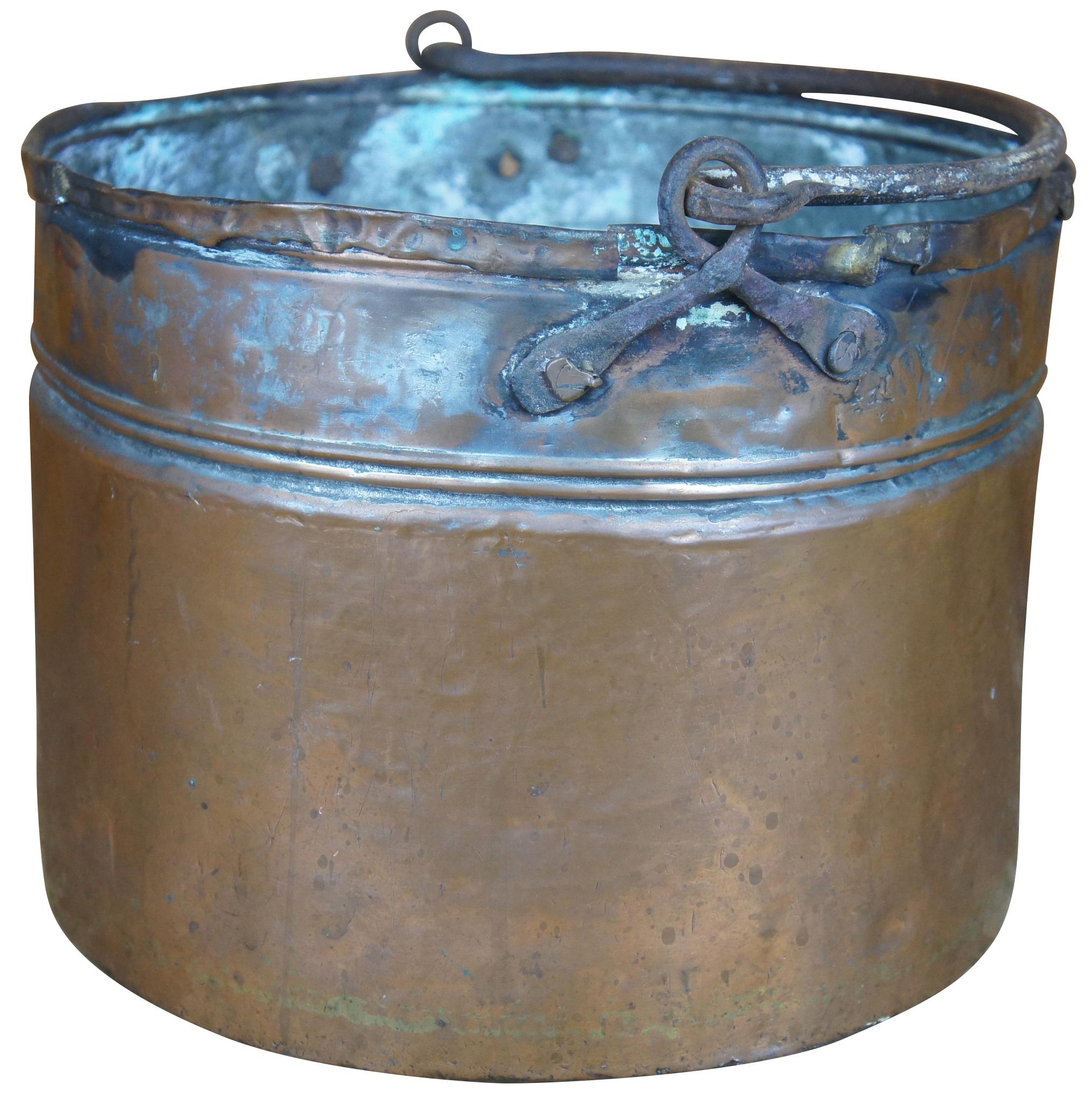 Antique 18th century hammered and dovetailed copper cauldron featuring ornate scrolled iron handle and double banding. Measures: 12