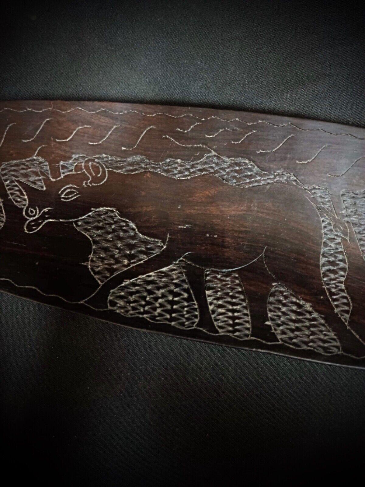This exquisite antique tray is crafted from precious wood and features a hand-carved design depicting a rhinoceros in a savanna landscape. A fine example of African art, this piece showcases detailed craftsmanship that adds a unique cultural touch
