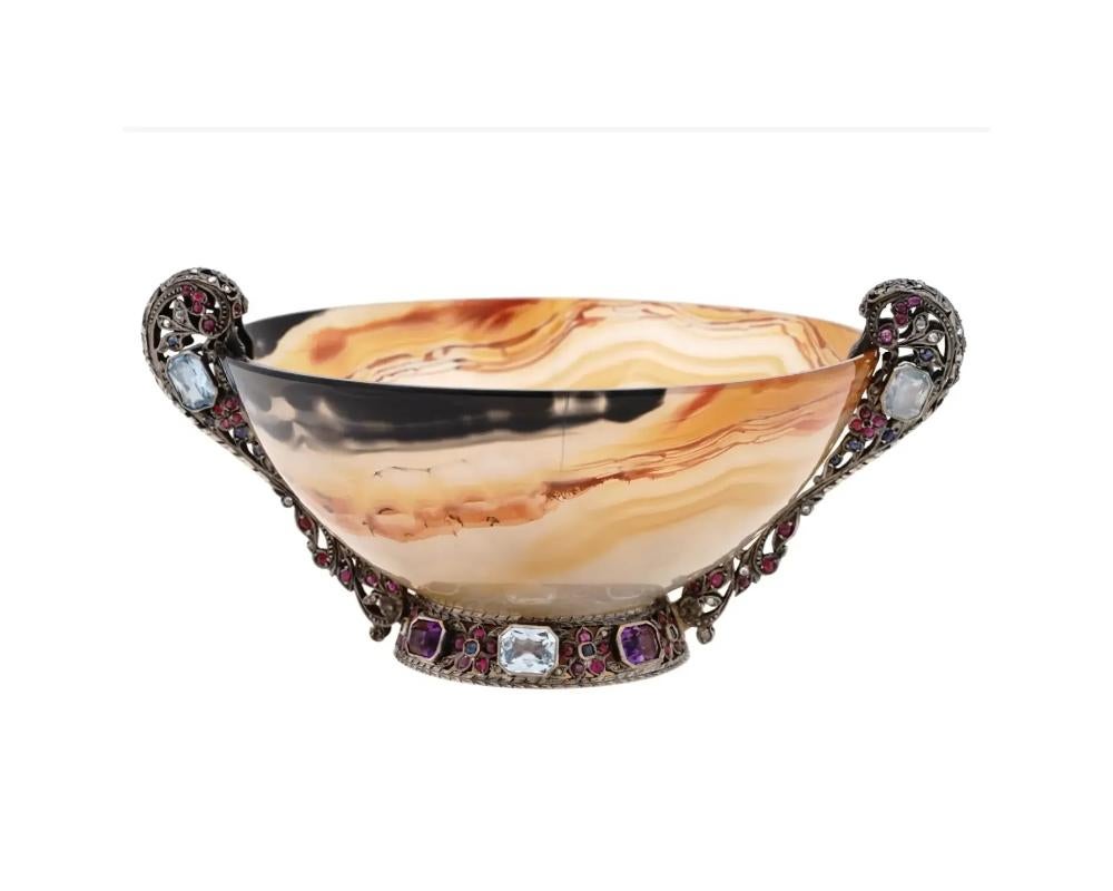 An antique hand carved agate bowl, showcasing the beauty of natural agate stone combined with intricate silver mounts adorned with precious gemstones. The carved agate bowl serves as a stunning canvas for showcasing the unique patterns and colors