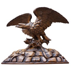 Antique sculpture à la main d'un aigle de la forêt noire:: ailes déployées sur un tronc d'arbre
