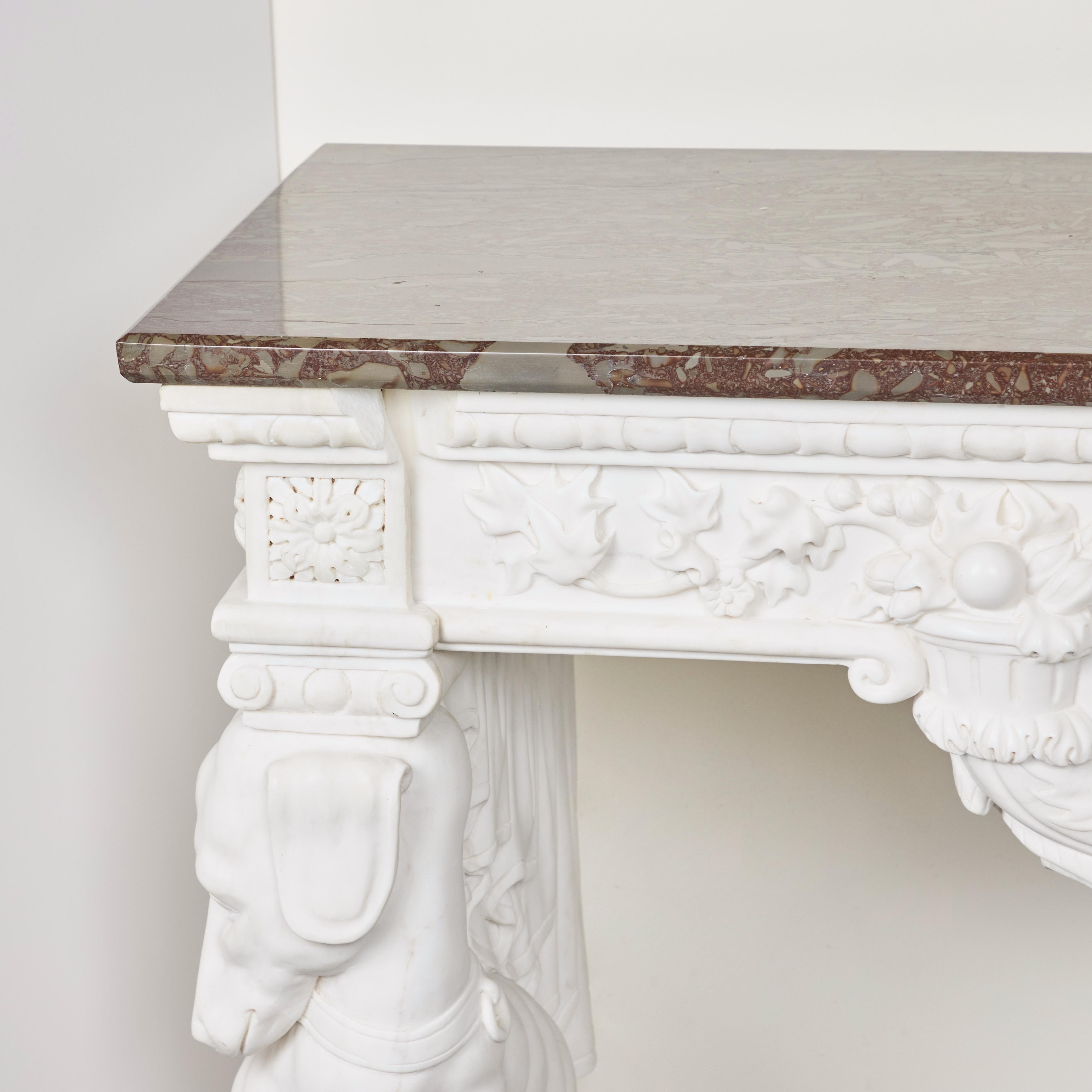 Beautifully hand-carved Carrara marble console table with seated hounds and a carved frieze with cartouche holding a marble top.   In 4 assembled pieces.
