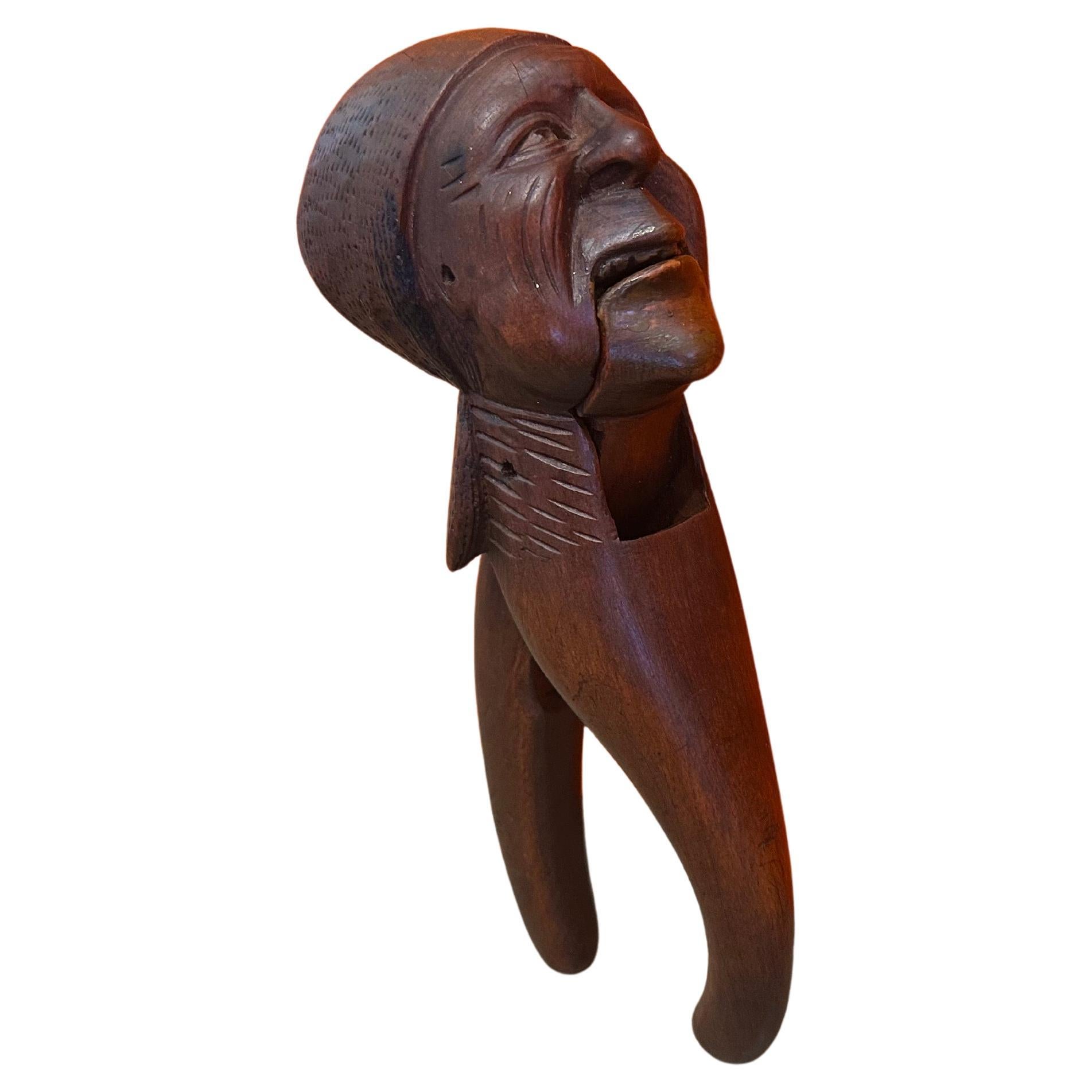 Very rare early 20th century antique Black Forest hand carved wood nutcracker with book. These particular pieces often feature anthropomorphic figures with exaggerated features, and this one is no exception. The figure's mouth opens to crack nuts!