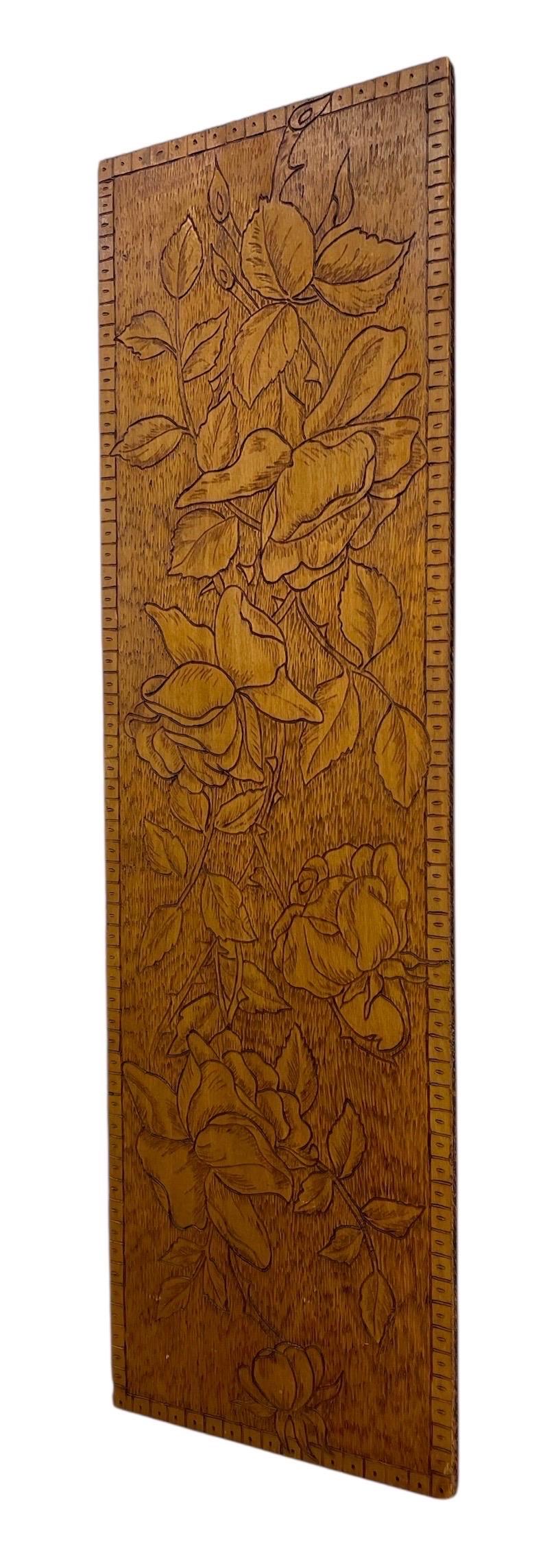 Panneau mural ancien en bois sculpté à la main présentant un motif floral complexe avec des roses et des feuilles encadrées par une bordure géométrique. La sculpture est exécutée en bas-relief, mettant en valeur les pétales détaillés, le feuillage