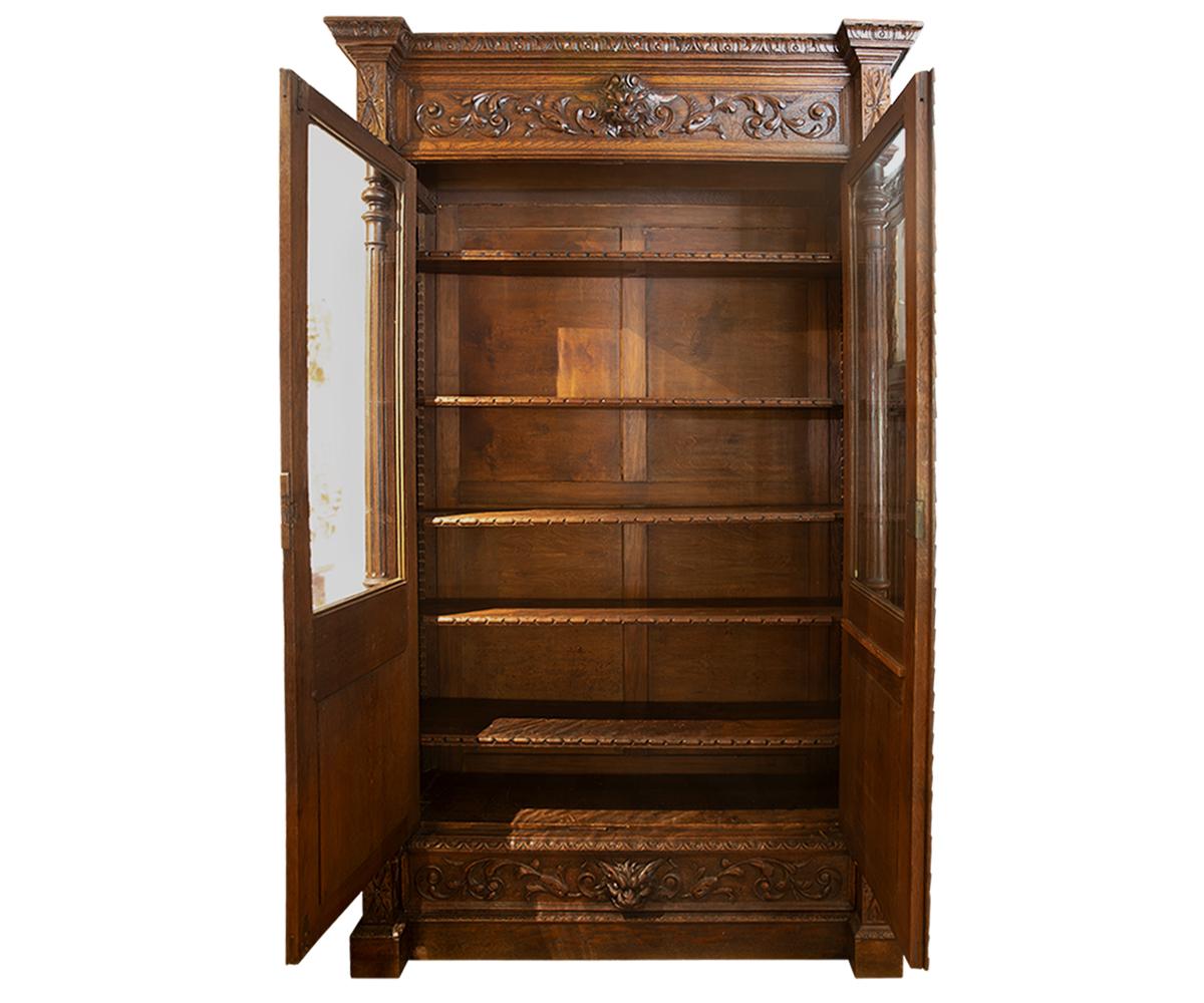 An outstanding antique hand carved French oak with a two-door bookcase and complimented inside shelves. On the left side of door is a carving of a musical instrument and on the right side a carving of books and feather pin. On the top and bottom