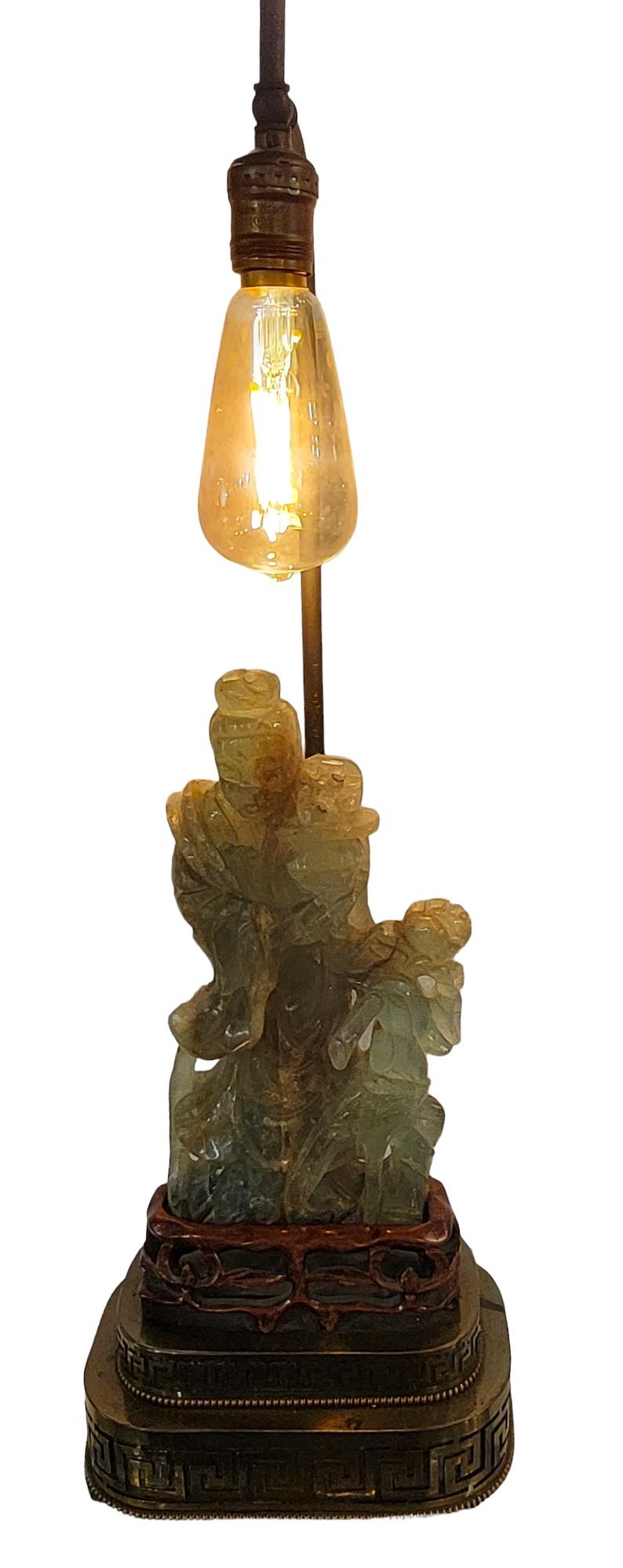 Antique Hand Carved Jade Table Lamp. Beautiful hand carved jade over a hand carved wooden stand. That stand sits snug above a brass lamp base. The base has a patinaed copper extension leading over he jade sculpture. 
Wear to jade sculpture from age