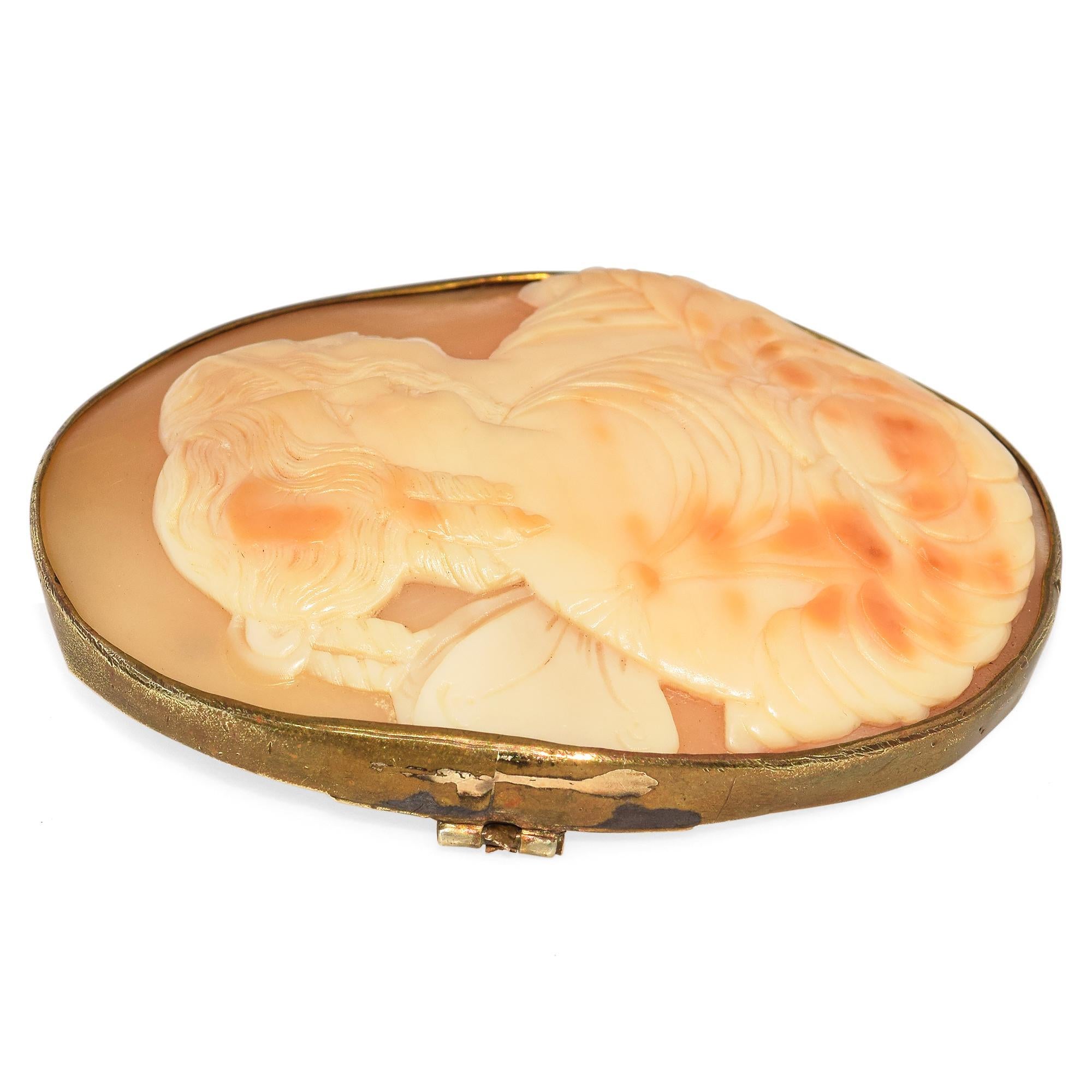 Diese antike, handgeschnitzte Muschelkamee-Brosche zeigt zwei geflügelte Musen in exquisiten Details. Der elegante Rahmen unterstreicht die weiche, ätherische Schönheit der Szene. Die feine Schnitzerei und der Vintage-Charme machen ihn zu einem