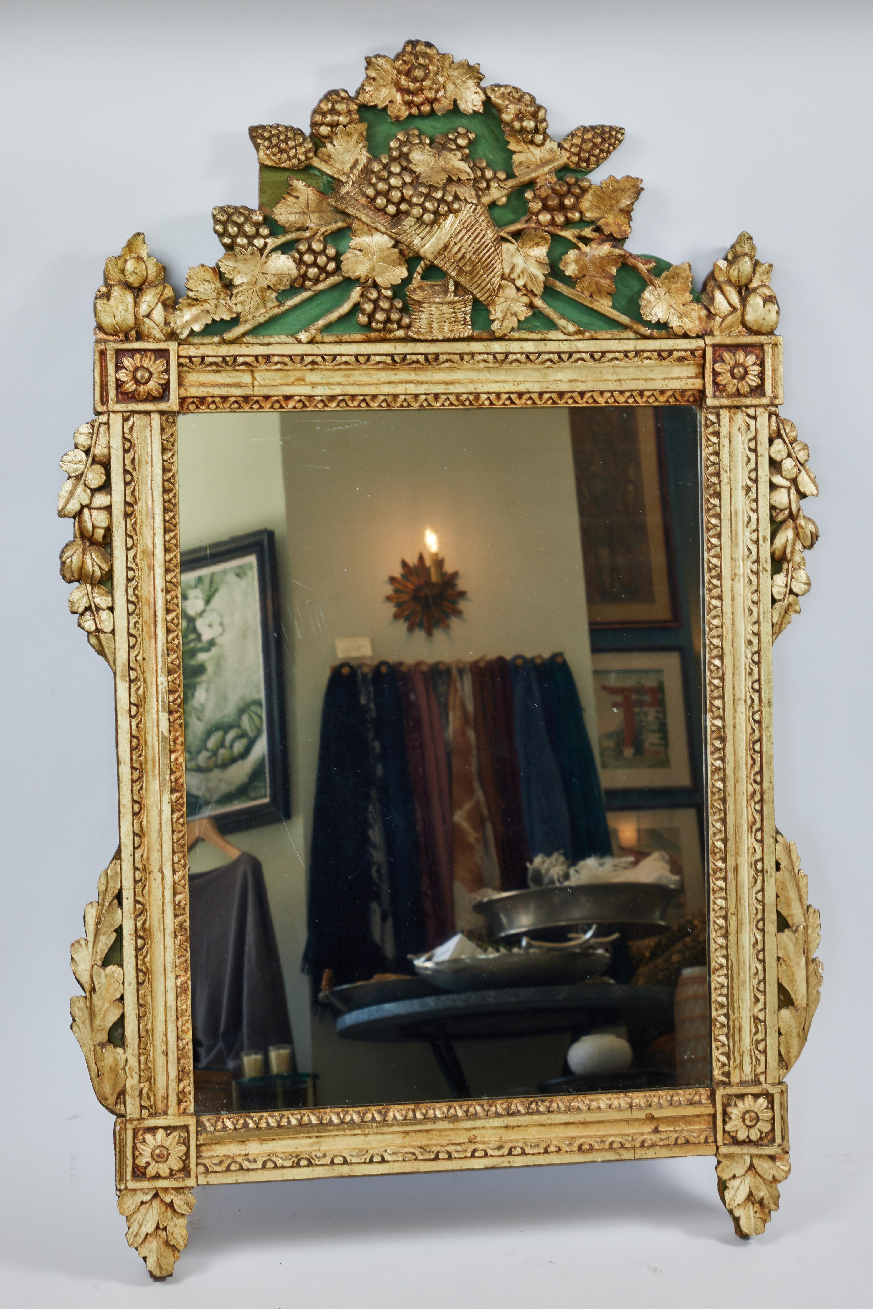 Miroir ancien en bois sculpté à la main, finition dorée d'origine

Elle présente un panier décoratif en forme de corne d'abondance et des vignes détaillées sur sa couronne, des motifs de feuilles complexes sur les côtés et le fond, des médaillons